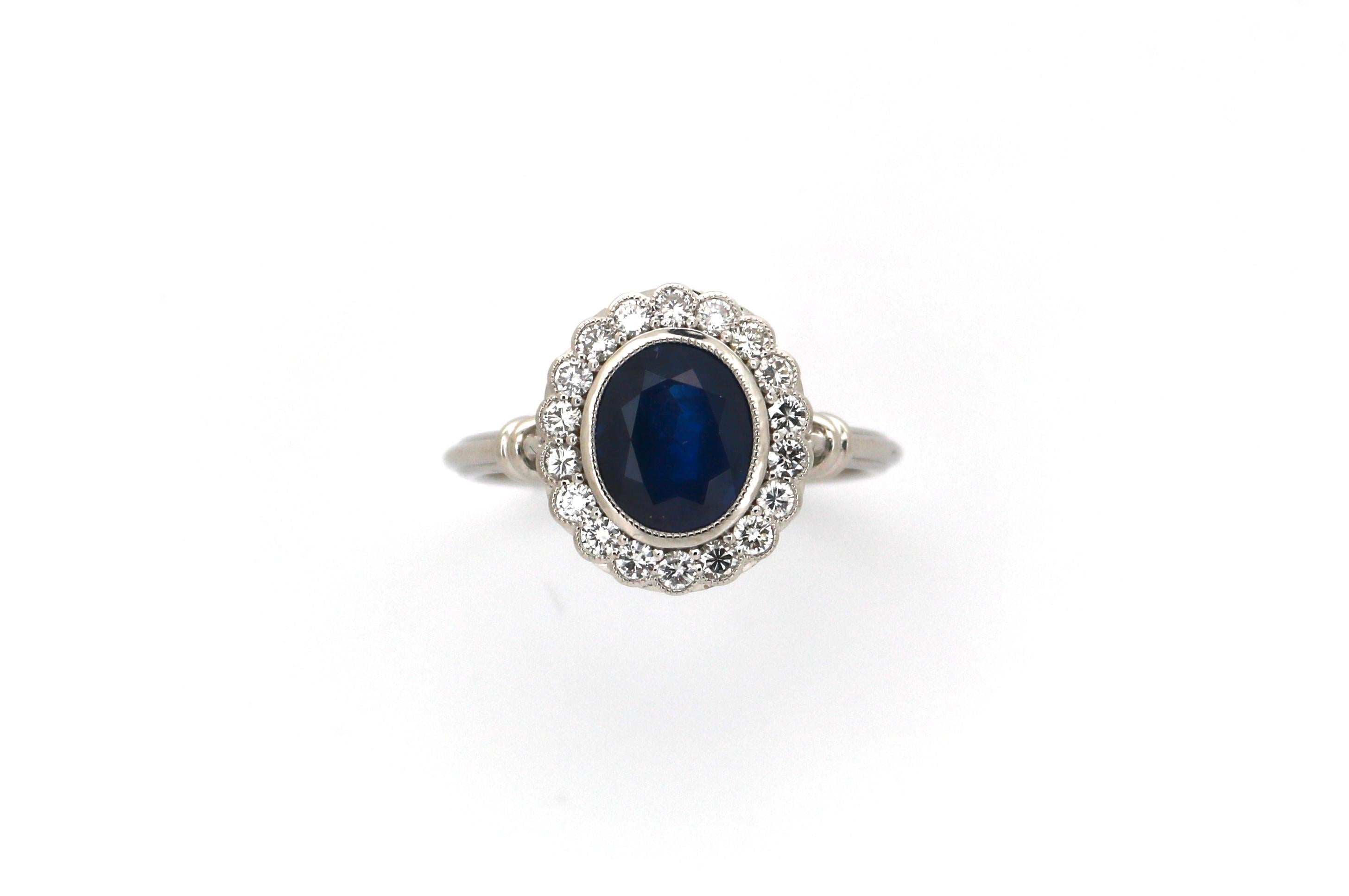 Bague unique en or blanc 18 carats sertie au centre d'un saphir bleu vif naturel de taille ovale pesant 2,57 carats et entourée de 18 diamants de taille brillant d'un poids total estimé à 0,40 carat. Le saphir a une belle couleur bleu foncé. 
La