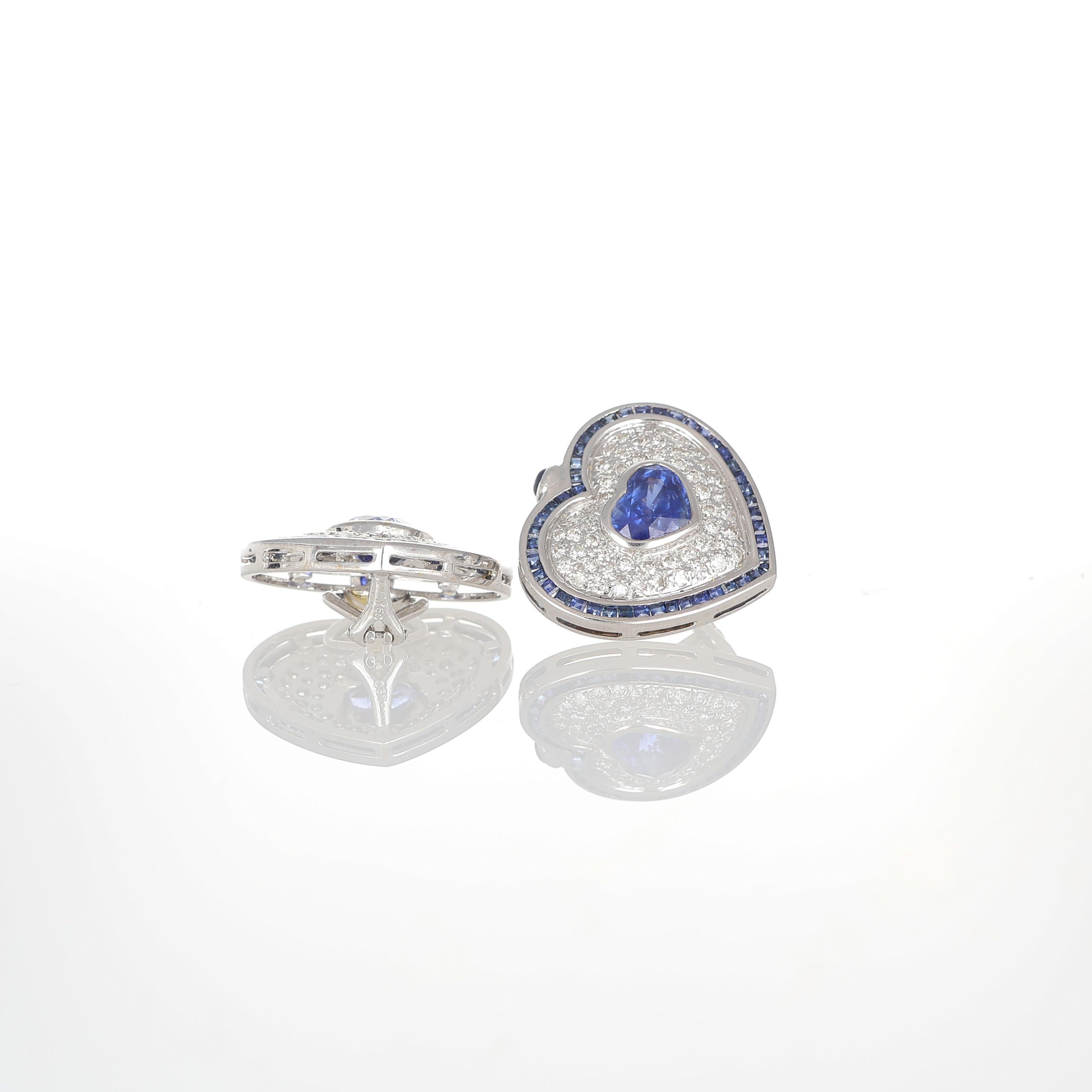 Elégantes boucles d'oreilles en forme de cœur réalisées en or blanc 18 carats, mettant en valeur d'exquis saphirs bleus au centre, taillés en forme de cœur romantique pour un total de 3,40 carats. Un pavage raffiné de diamants blancs taille