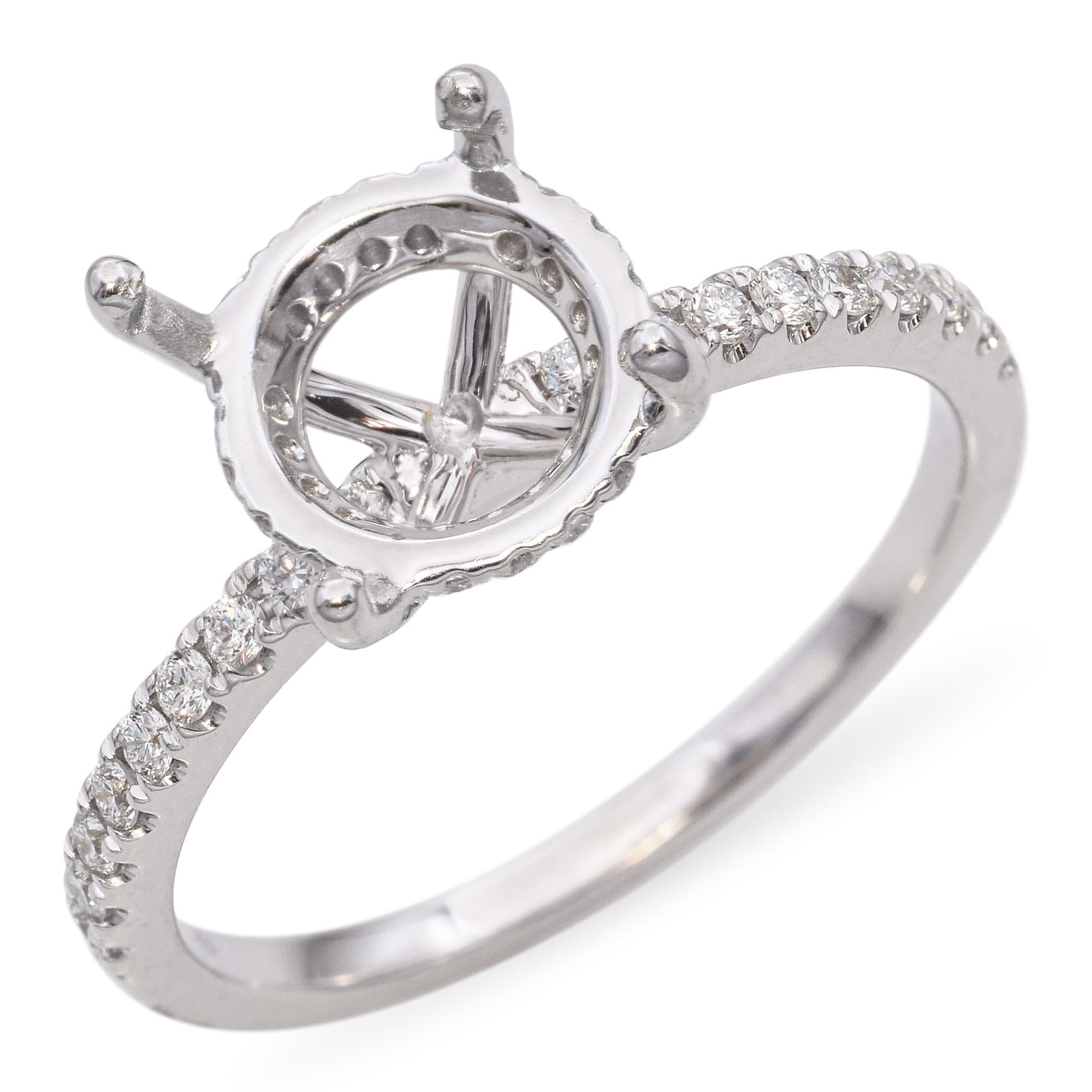Elaborado en oro blanco de 18 quilates, este anillo de compromiso presenta diamantes blancos redondos en la mitad de la banda, con diamantes adicionales alrededor de la galería. Completa el anillo con una piedra central redonda de tu