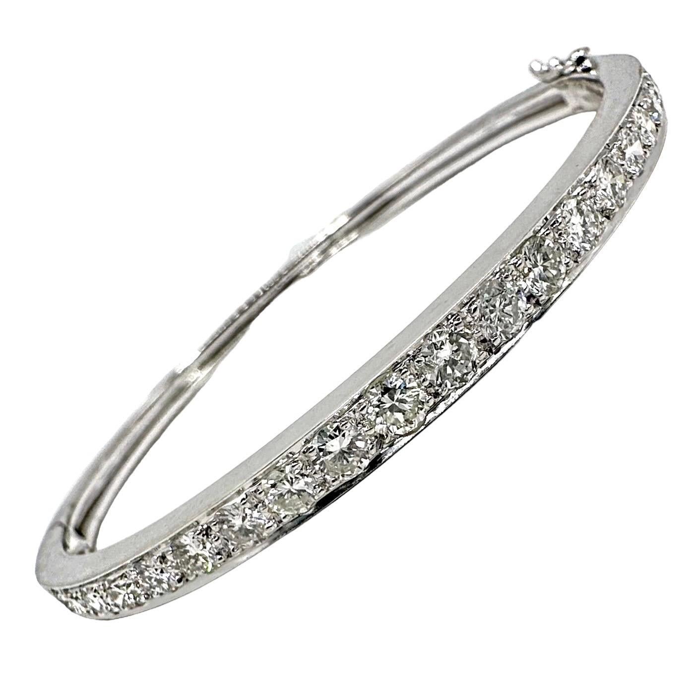 An easy to wear, oval shaped, 18K White gold hinged bangle with brilliant cut diamonds spanning the top. The 23 diamonds weigh a total 2.20ct of overall G/H color and VS2 clarity. The diamonds are prong set inside a channel. The crisp, flat edges