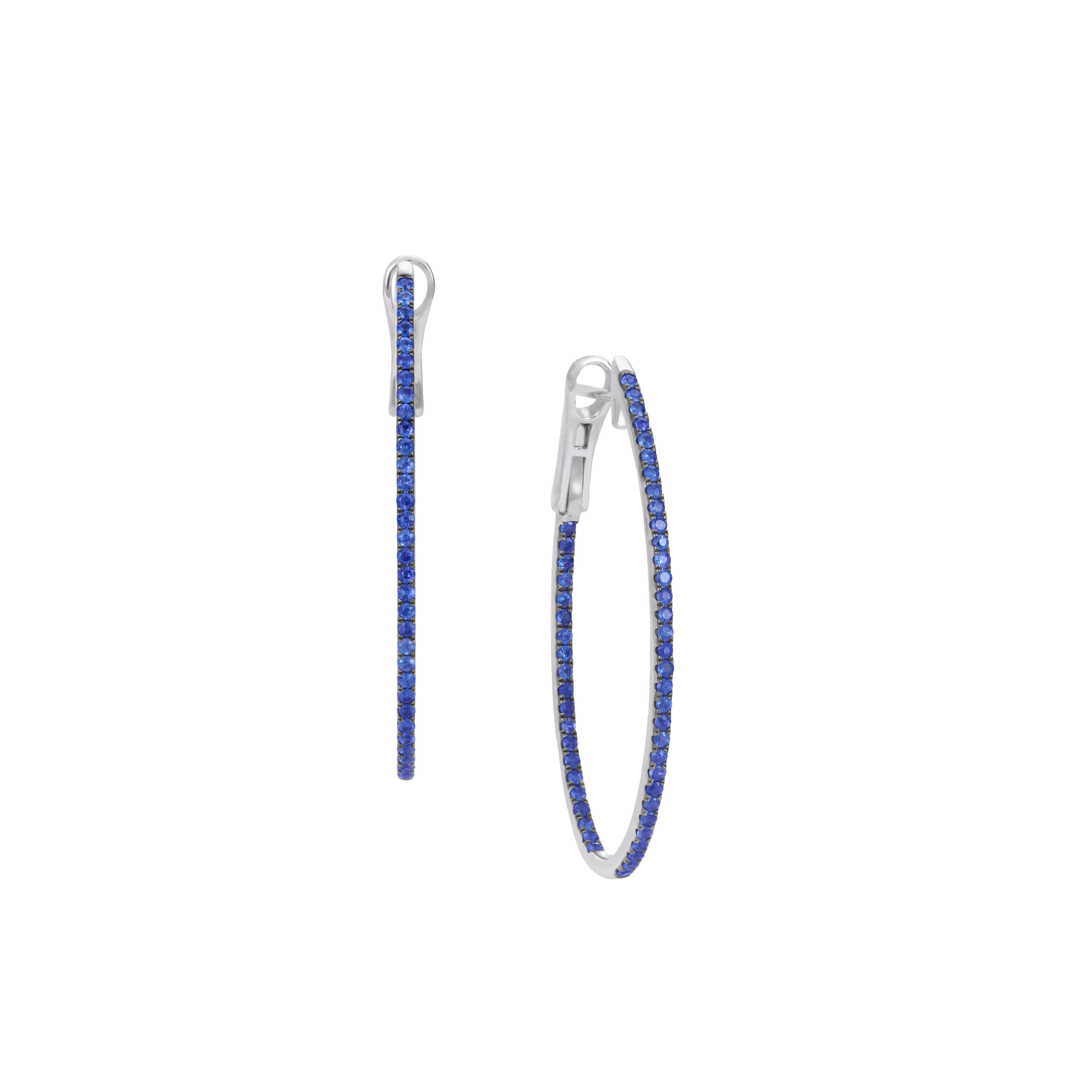 The unique pair of sapphire hoop earrings are made of 18K white gold. On the gold body of the earrings, there are exotic round cut African blue sapphires encrusted in a micro pave setting. In these gold hoop earrings, the total weight of the