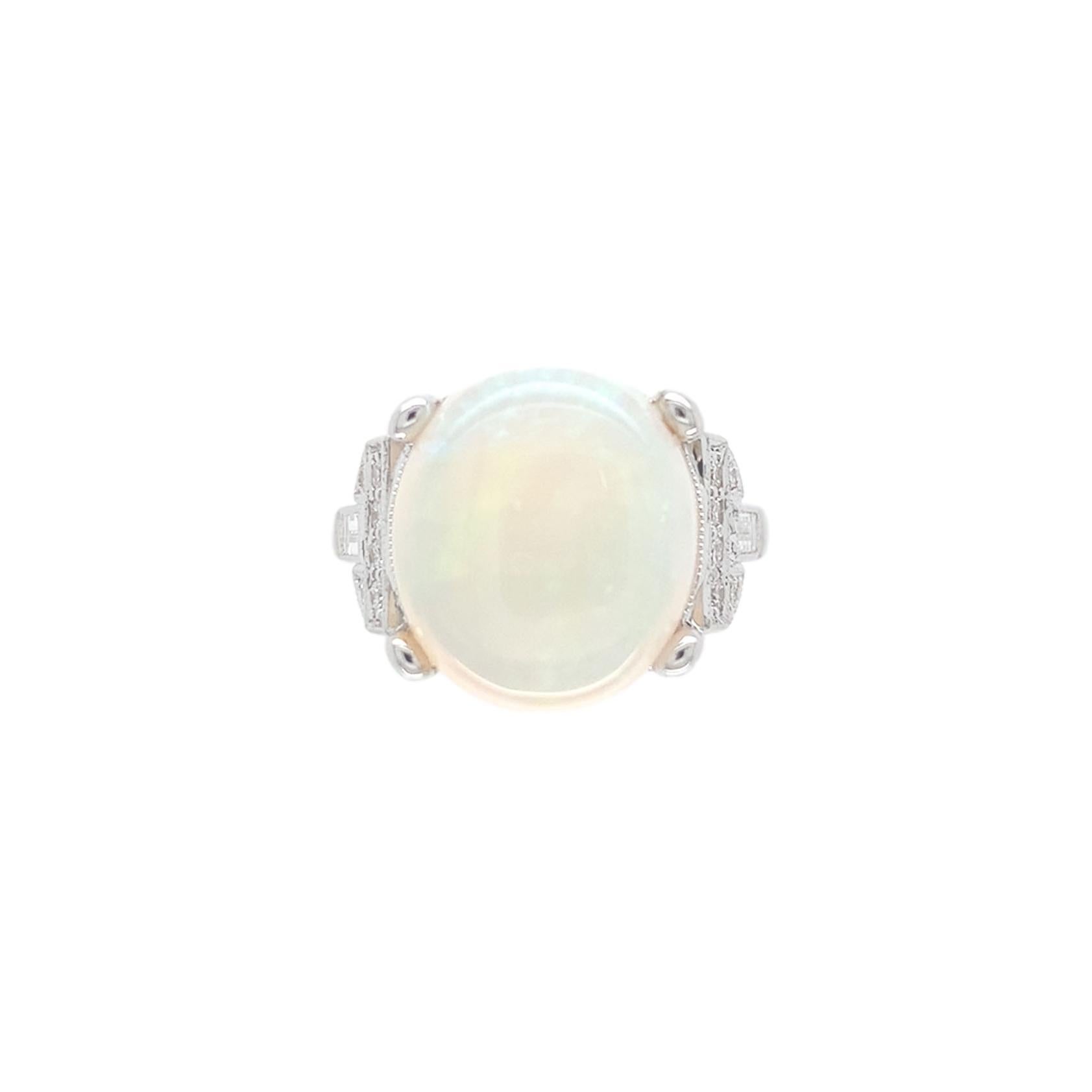 18k white gold ring featuring a large oval Australian opal weighing 6.88 carats.  The natural white opal has primarily pink-red and green play of color.  The opal measures about 13.7mm by 12mm.  There are 12 small round brilliant cut and 2 baguette