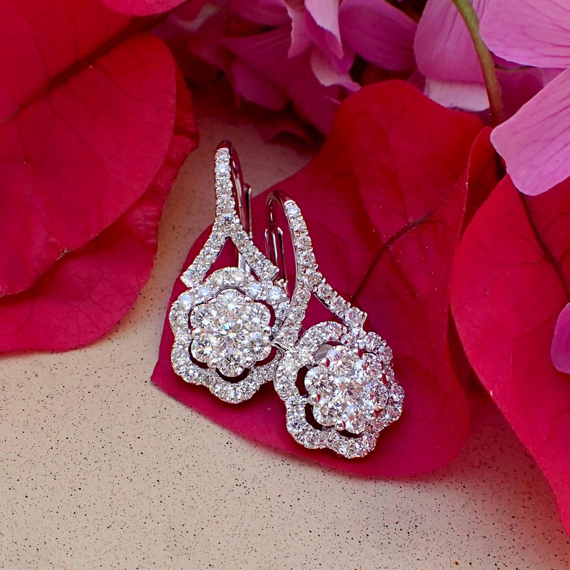 A pair of 18k white gold earrings have two (2) Round Brilliant Cut diamonds weighing a total of 0.12 carats with Clarity Grade VS and Color Grade G and seventy (70) Round Brilliant Cut diamonds weighing a total of 0.89 carats with Clarity Grade VS