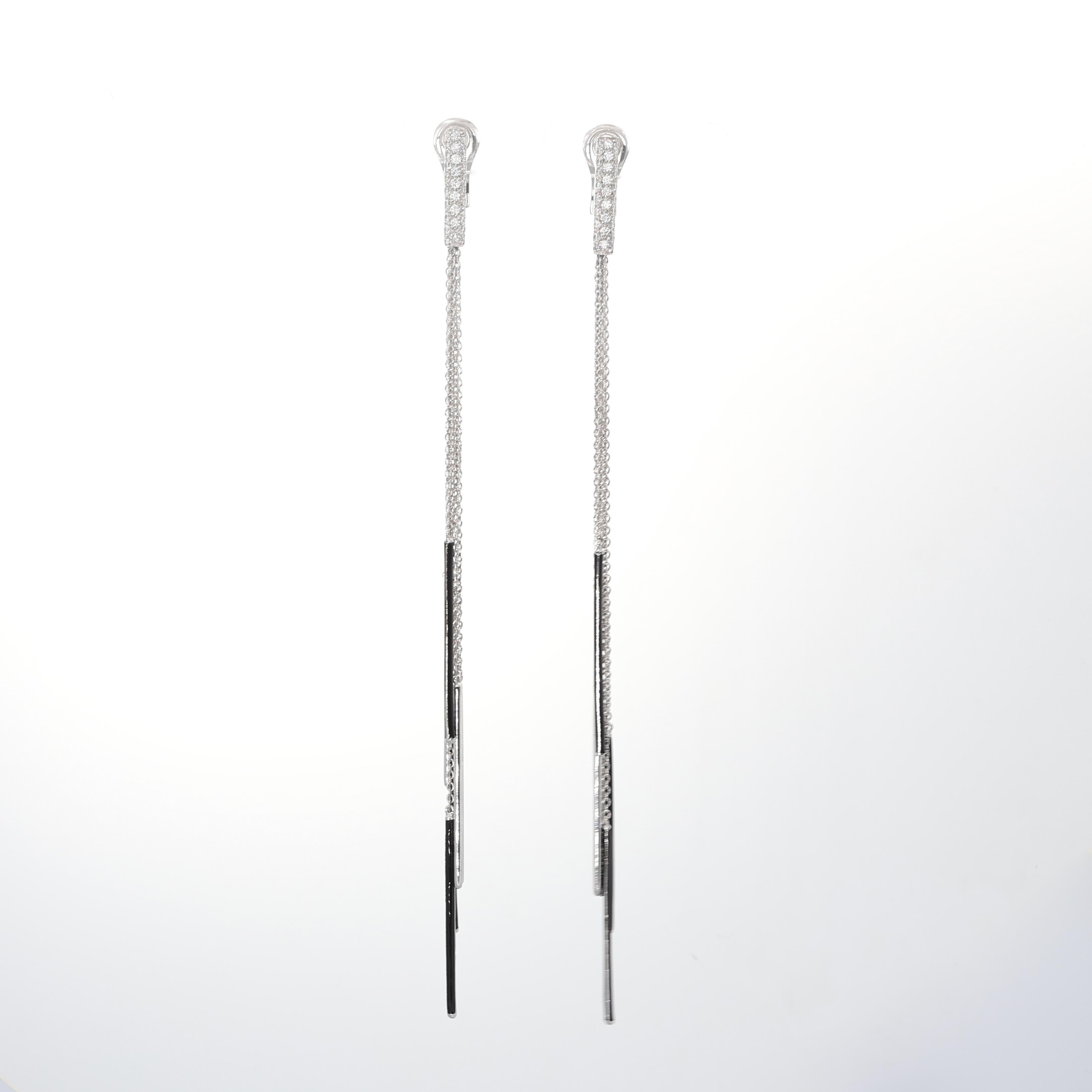 A sleek and contemporary design, these 18K white gold earrings feature delicate diamond-studded chains with geometric black enamel bars. The contrast between the shimmering diamonds and the deep black enamel creates a bold yet refined look. With