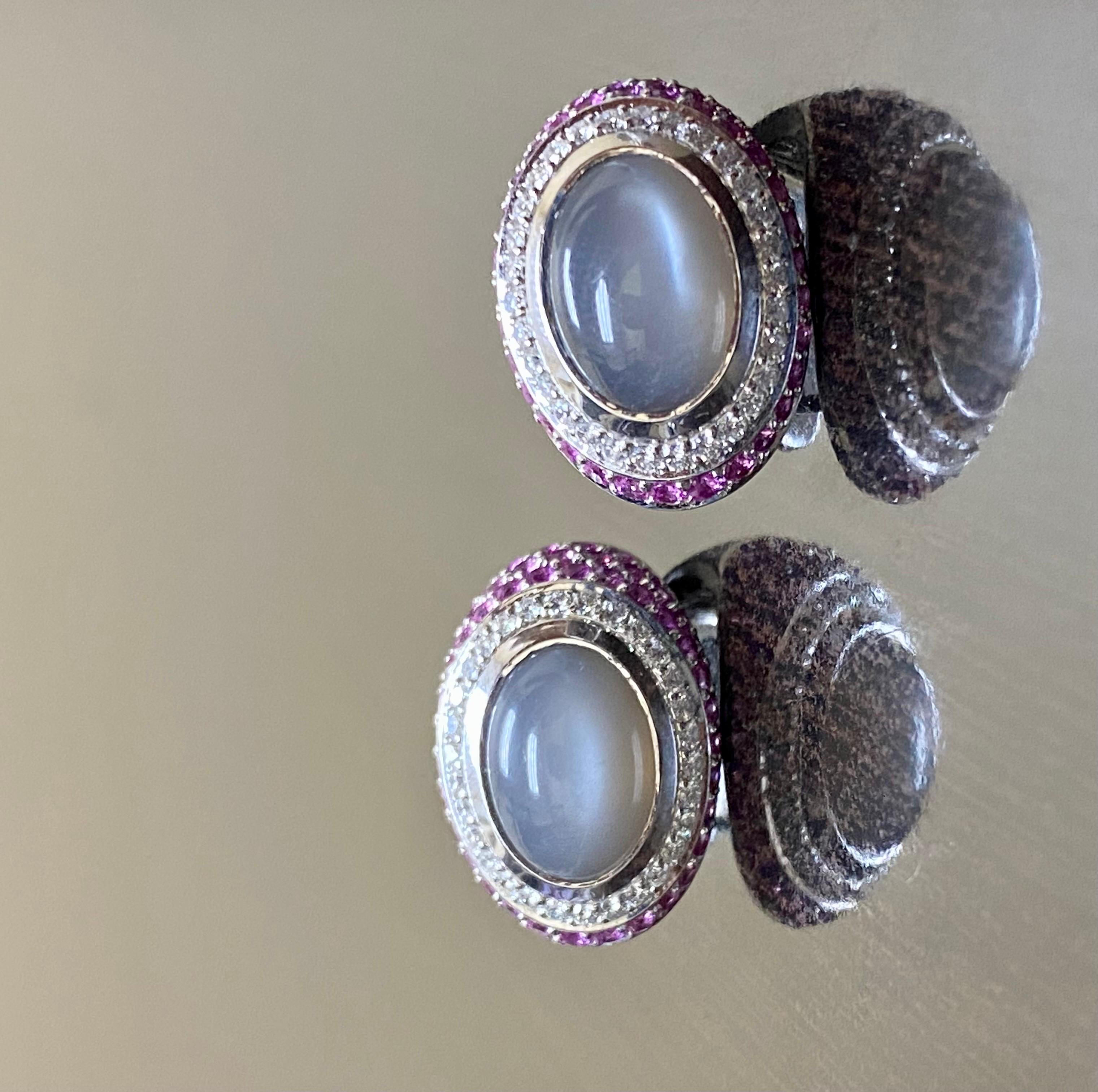 DeKara Designs Collection

Beautiful Art Deco/Modern/Vintage Style Diamond and Pink Sapphire Oval Moonstone Earrings.

Metal- 18K White Gold, .750. 24 Grams.

Stones- 2 Genuine Oval Bluish Grey Moonstones 13x9 mm 9.74 Carats, 60 Round Diamonds F-G