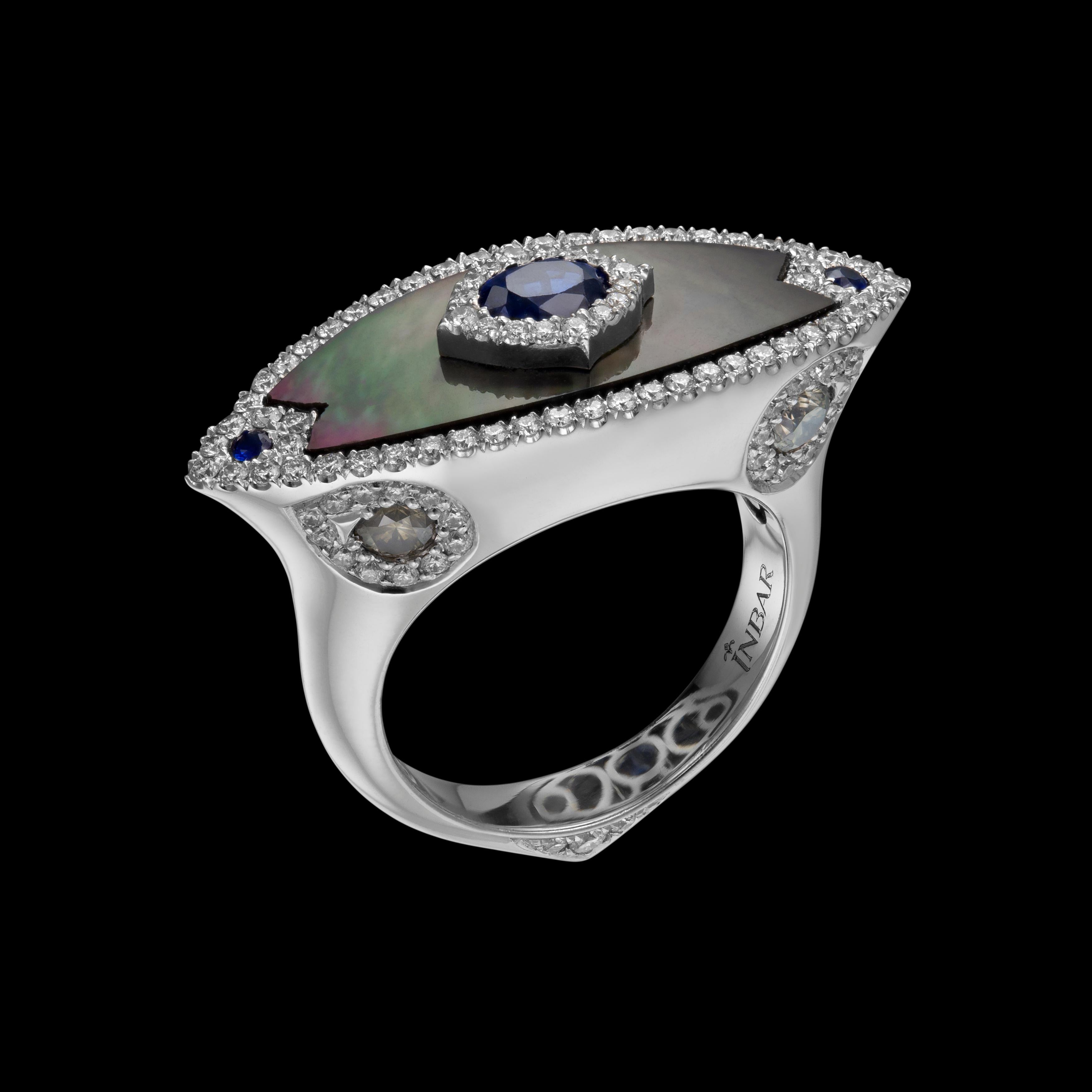 East west Mother of pearl and diamond ring set with a center sapphire.