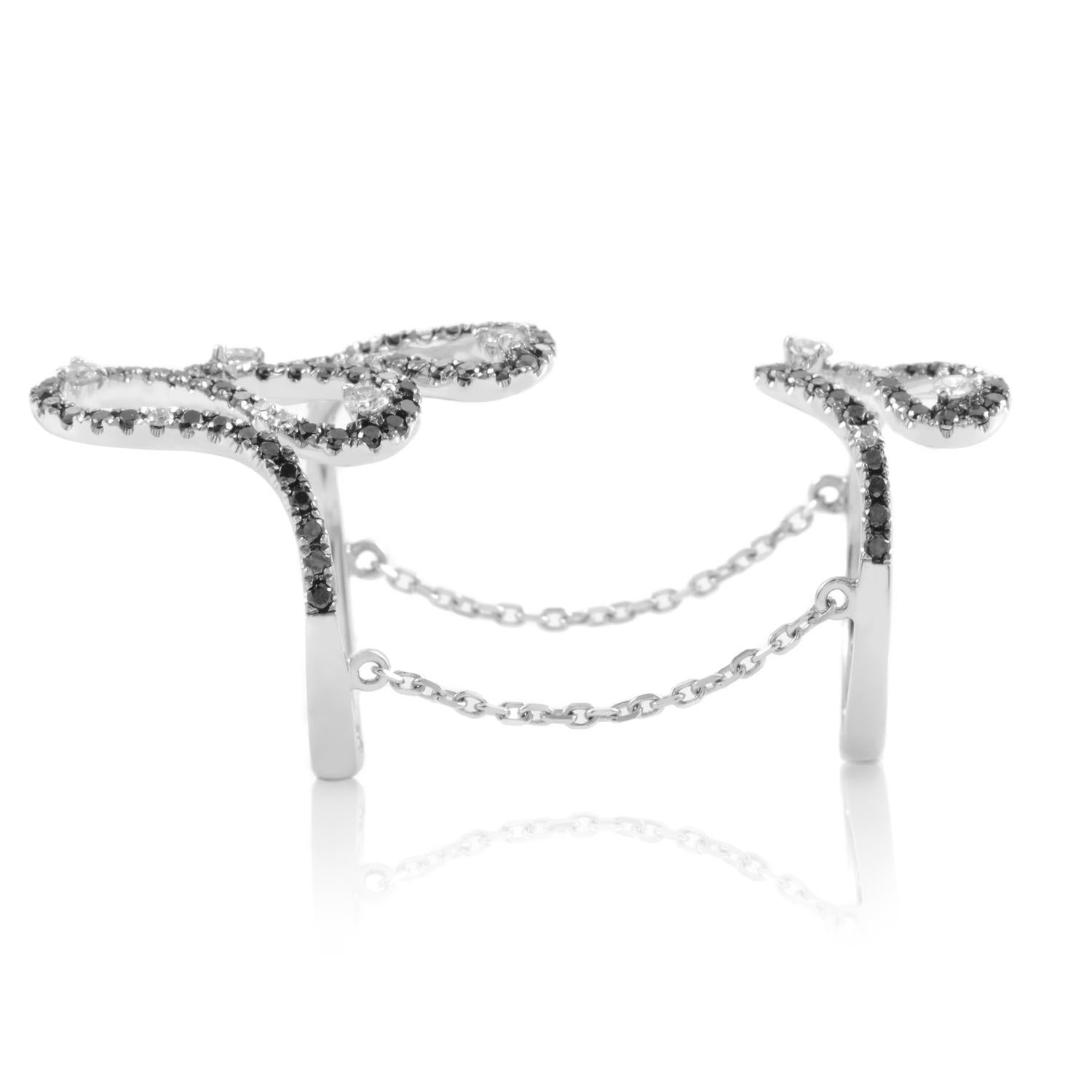 This alluring piece of jewelry is a very uniquely designed, contemporary ring. It consists of two separate rings linked together by an 18K white gold chain. The crowns of the two rings are sensationally set with black and white diamonds.

