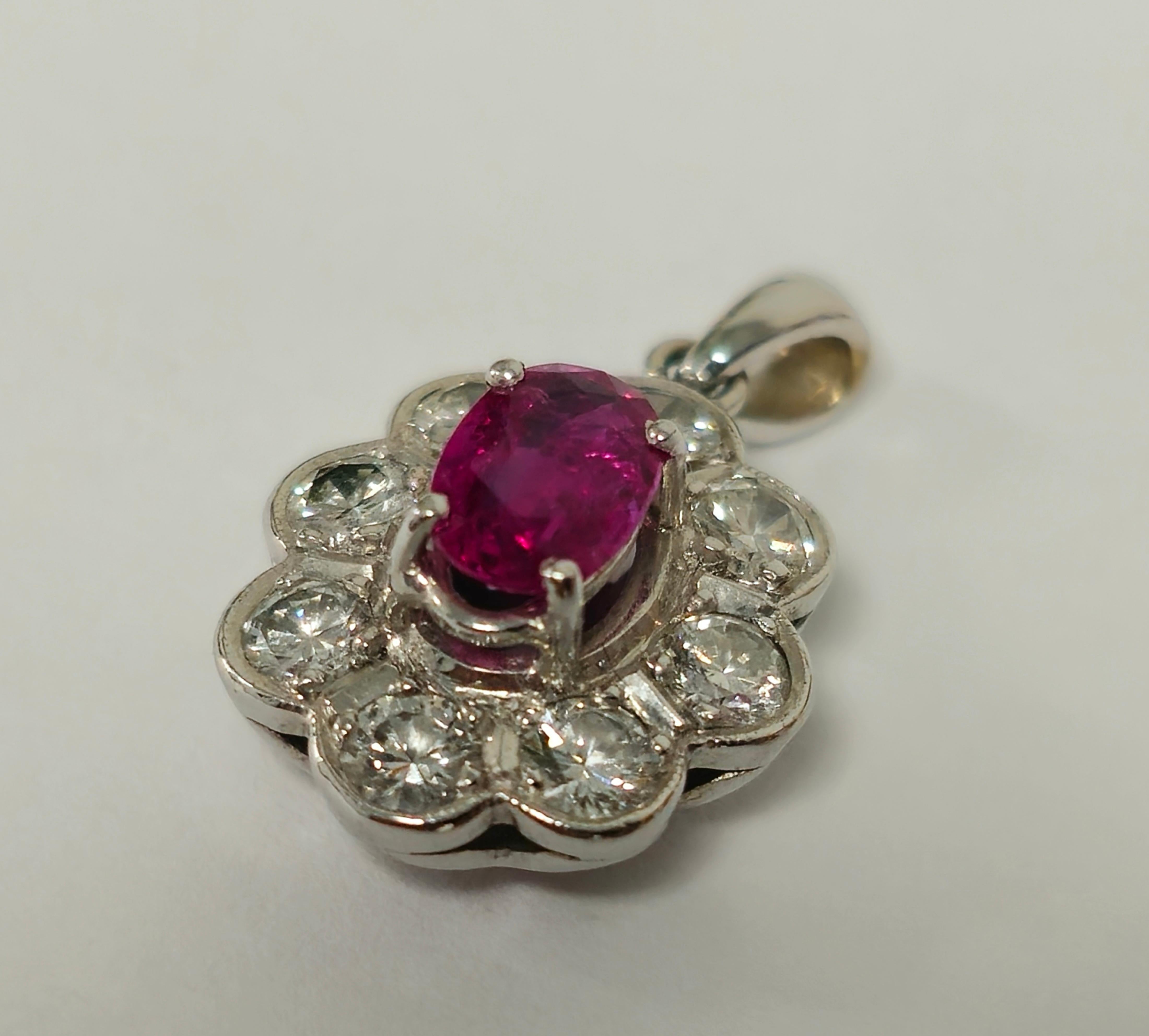 Crafted in stunning 18K white gold, this pendant boasts a captivating design featuring a mesmerizing oval-cut, no-heat ruby, exuding vibrant allure in its natural beauty. Surrounding the ruby are brilliant white diamonds of exceptional quality,