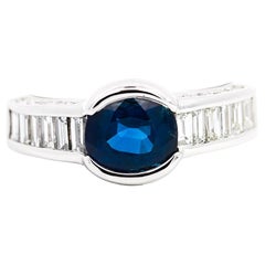Anillo de oro blanco de 18 quilates con zafiro azul ovalado y diamante baguette engastado en canal y bisel