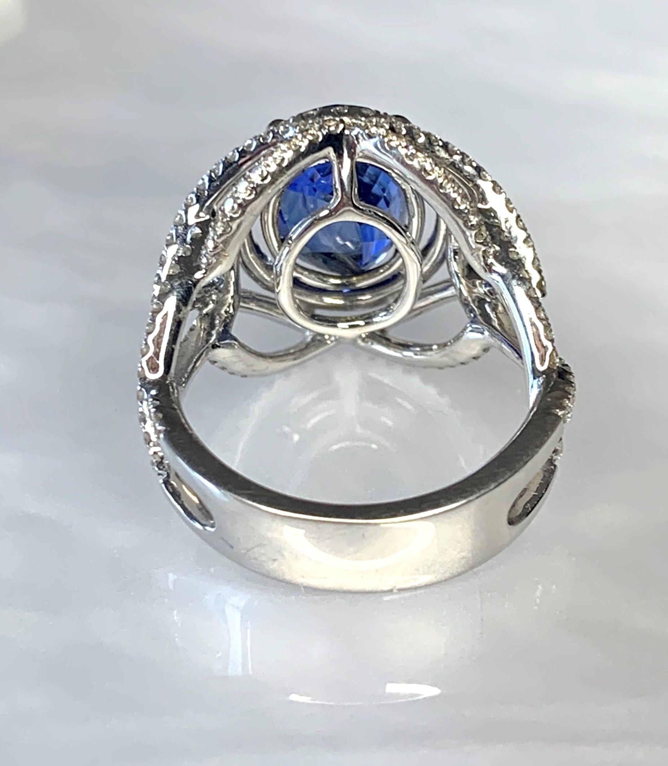 This phenomenal rich blue genuine sapphire ring is a true work of art. It features a vibrant oval center stone weighing 5.05 carats surrounded by 1.11 carats of sparkling white diamonds which have been intricately detailed with master craftsmanship