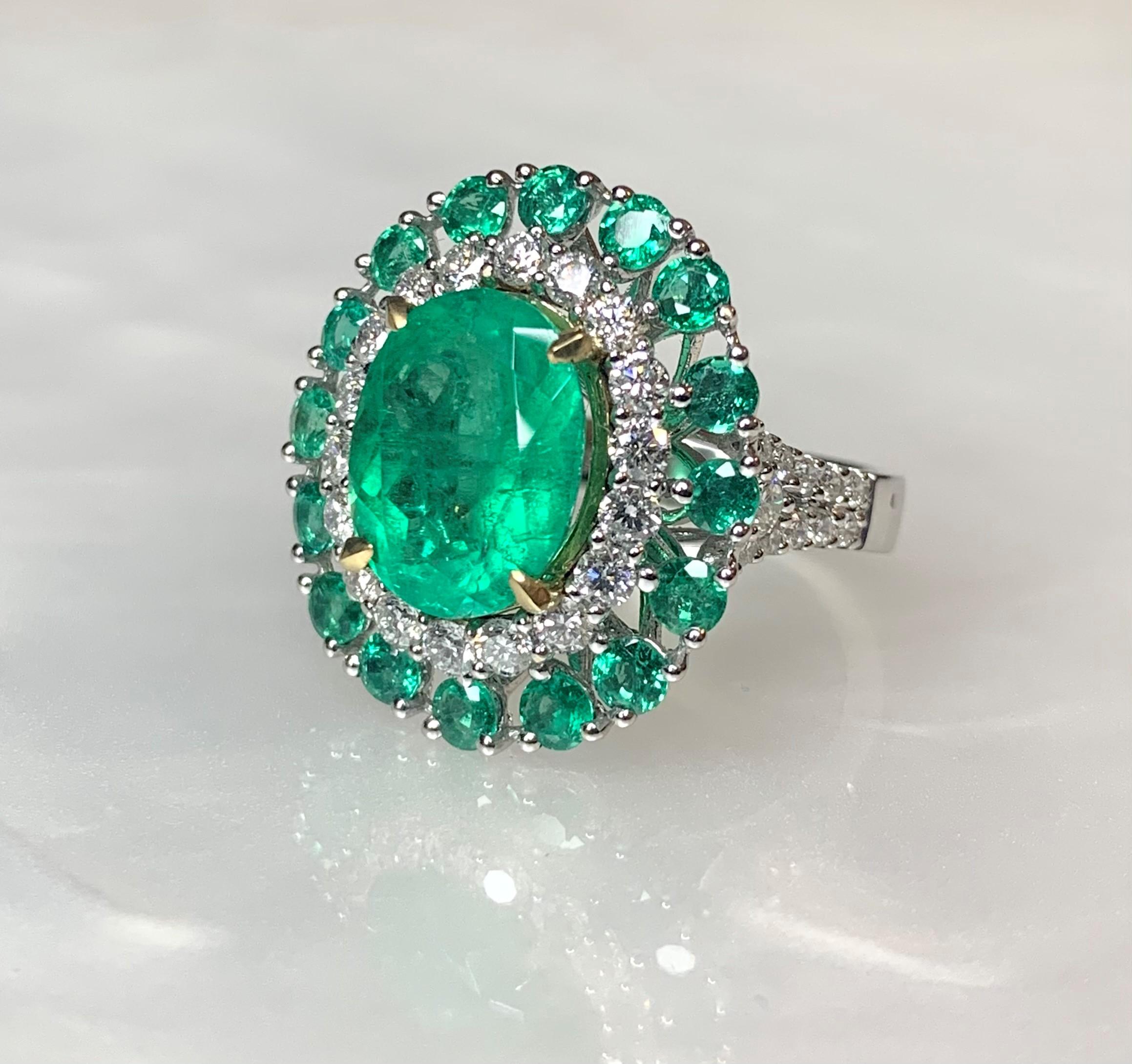 An enchanting candy colored Colombian emerald ring featuring a unique oval center stone weighing 4.44 carats surrounded by 16 emeralds weighing 1.32 carats and a halo of diamonds with a total weight of 1.27 carats.

*Approximate stone