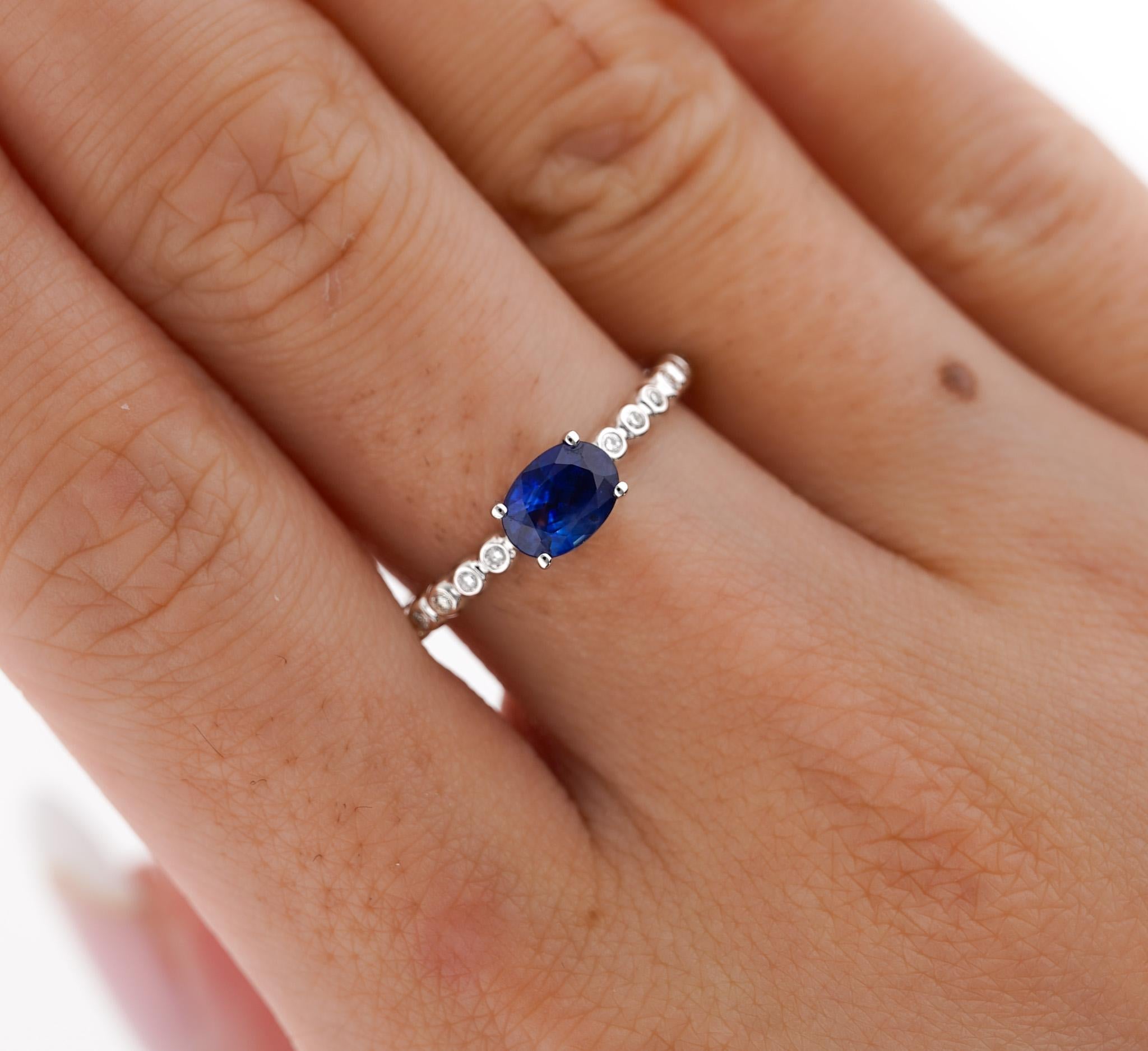 Natural Blue Sapphire and Natural Diamond Stacking Ring, Set in 18K White Gold. 

Featuring a textured ribbed bezel set of diamond side stones and a vivid oval cut Blue Sapphire. Dainty 2mm thin band width makes it ideal as a stacked band or wearing