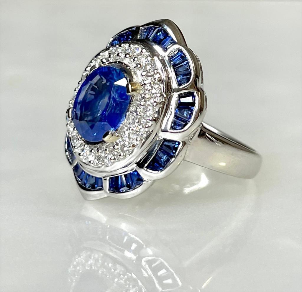 A delightful and dreamy vintage blue sapphire ring featuring an oval shaped sapphire center stone weighing 1.30 carats surrounded by 0.75 carats of sparkling white diamonds and accented by 1.85 carats of square cut blue sapphires set in solid 18K