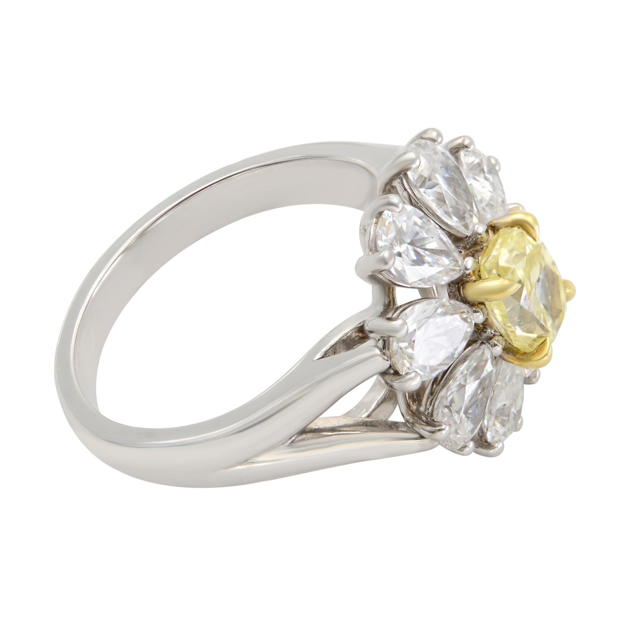A beautiful classic cocktail ring with 0.80 carat Fancy Yellow Oval cut as a center stone surrounded with 8 pear shaped diamonds of 1.90 carat in a Halo design adorned in a filigree pattern compliments the Fancy yellow gem. This truly striking