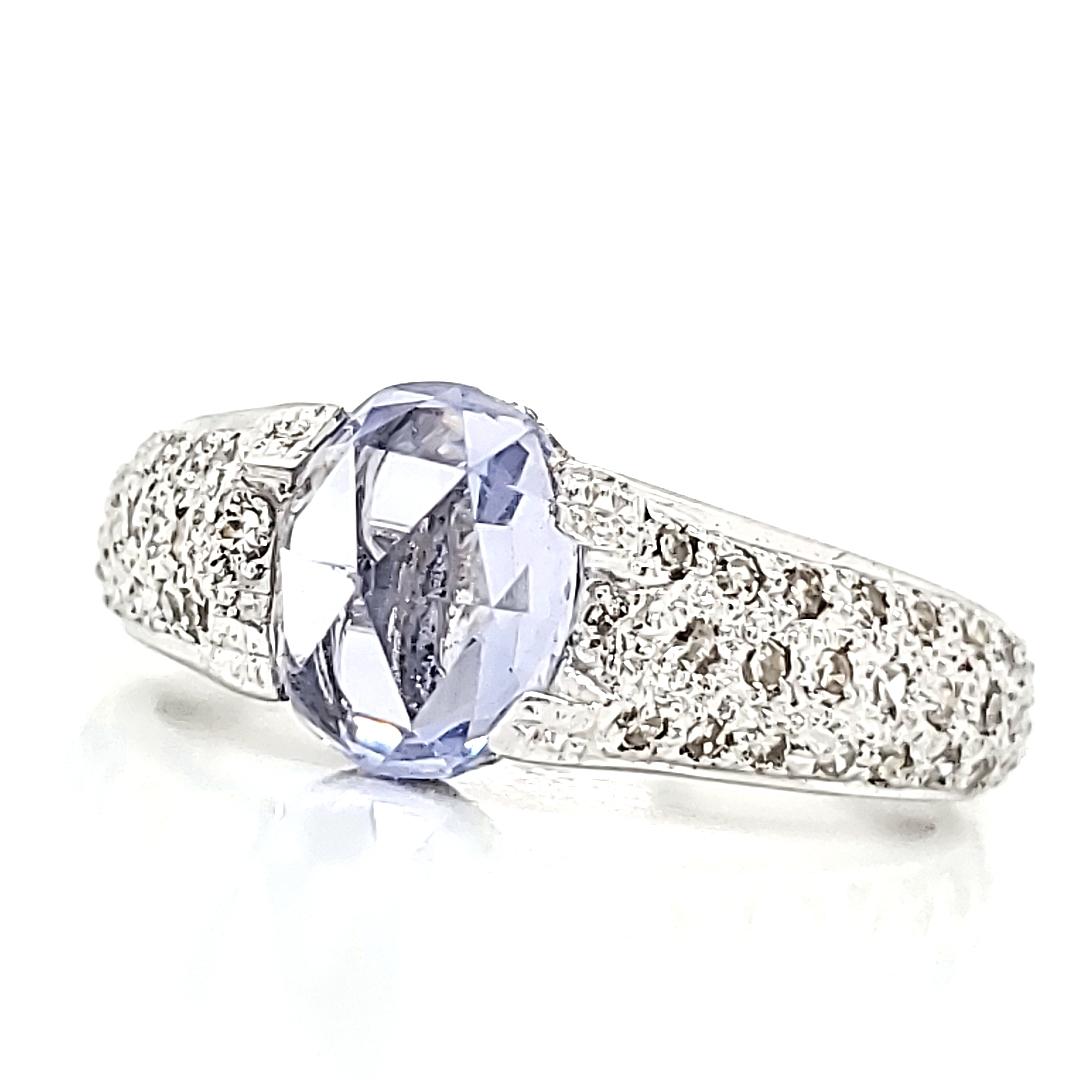 This enchanting piece boasts a captivating 1.95-carat oval-shaped rose-cut blue sapphire and is certified to have undergone no heat treatment.

It is gracefully accented by 0.69 carats of round diamonds.

All set in a luminous 18k white gold band