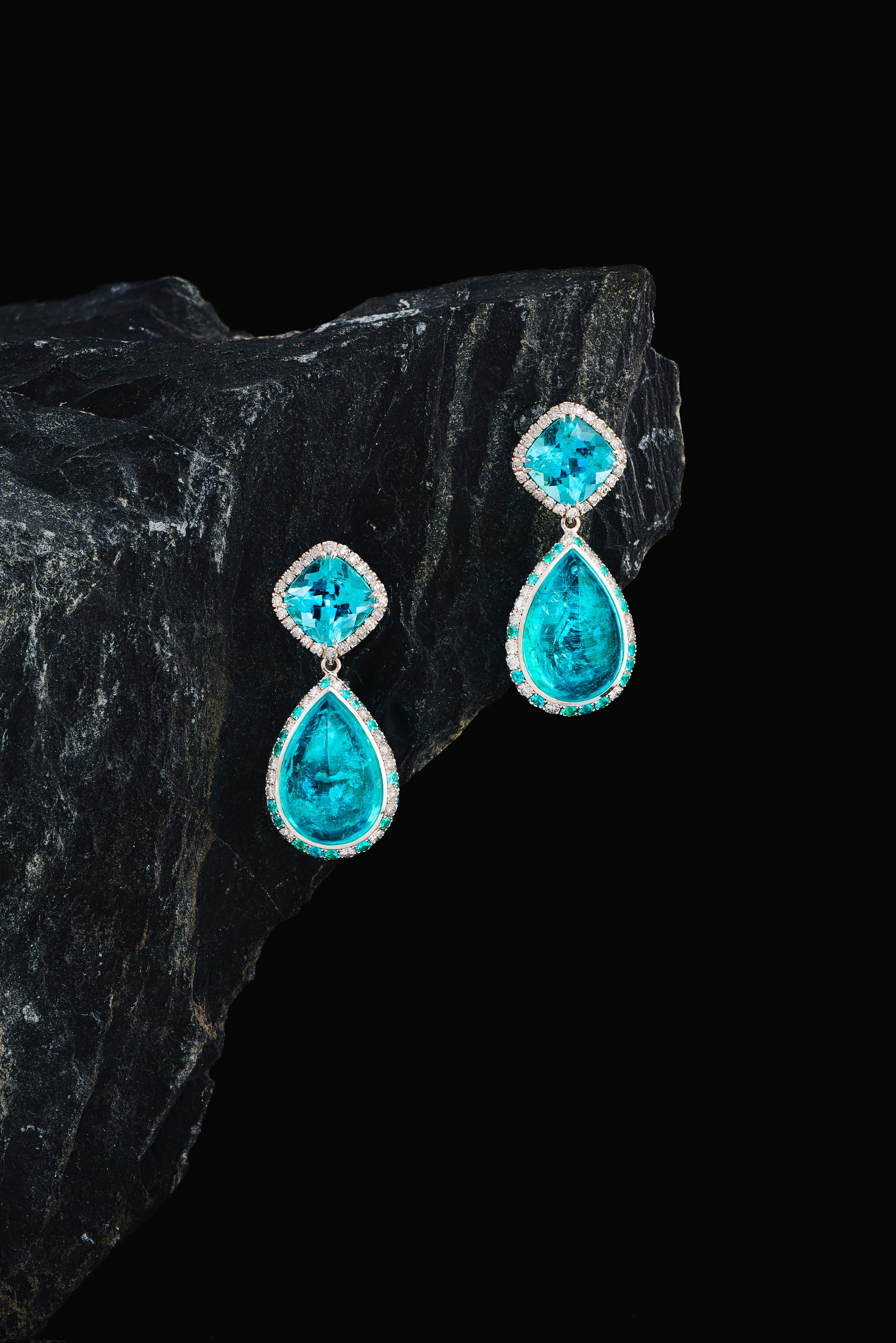 These one-off earrings are handmade in Switzerland. The earrings are made in 18K white gold with two pear shaped Paraiba Tourmaline Cabochons of total 14.49 ct. in entourage of 62 Paraiba Tourmalines of together 0.68 ct. and 59 Diamonds of total