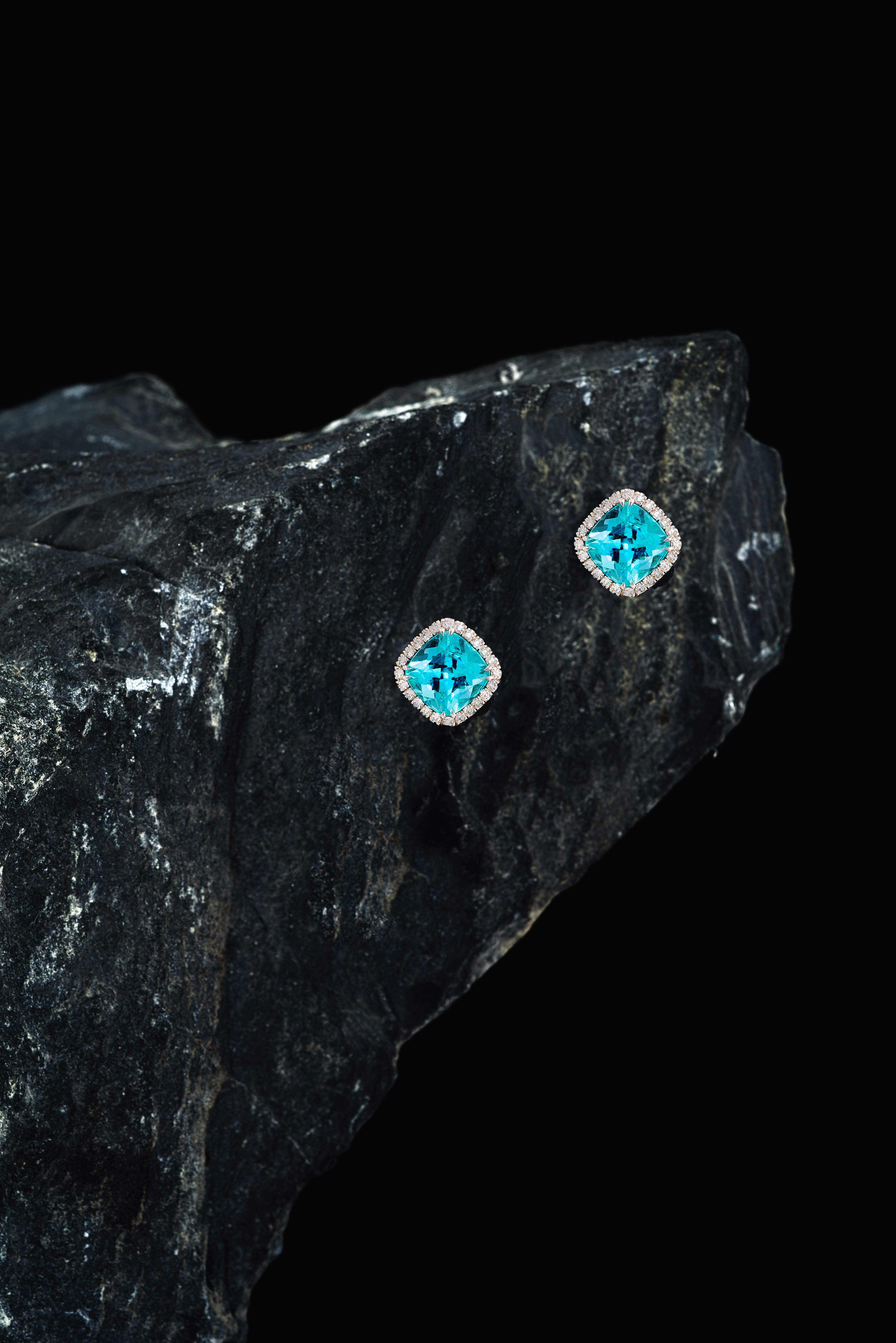 These one-off earrings are handmade in Switzerland. The earrings are made in 18K white gold with two cushion cut Paraiba Tourmalines of total 4.65 ct. in entourage of Paraiba Tourmalines and Diamonds of total 0.30 ct. F vvs. 
The Paraiba Tourmalines