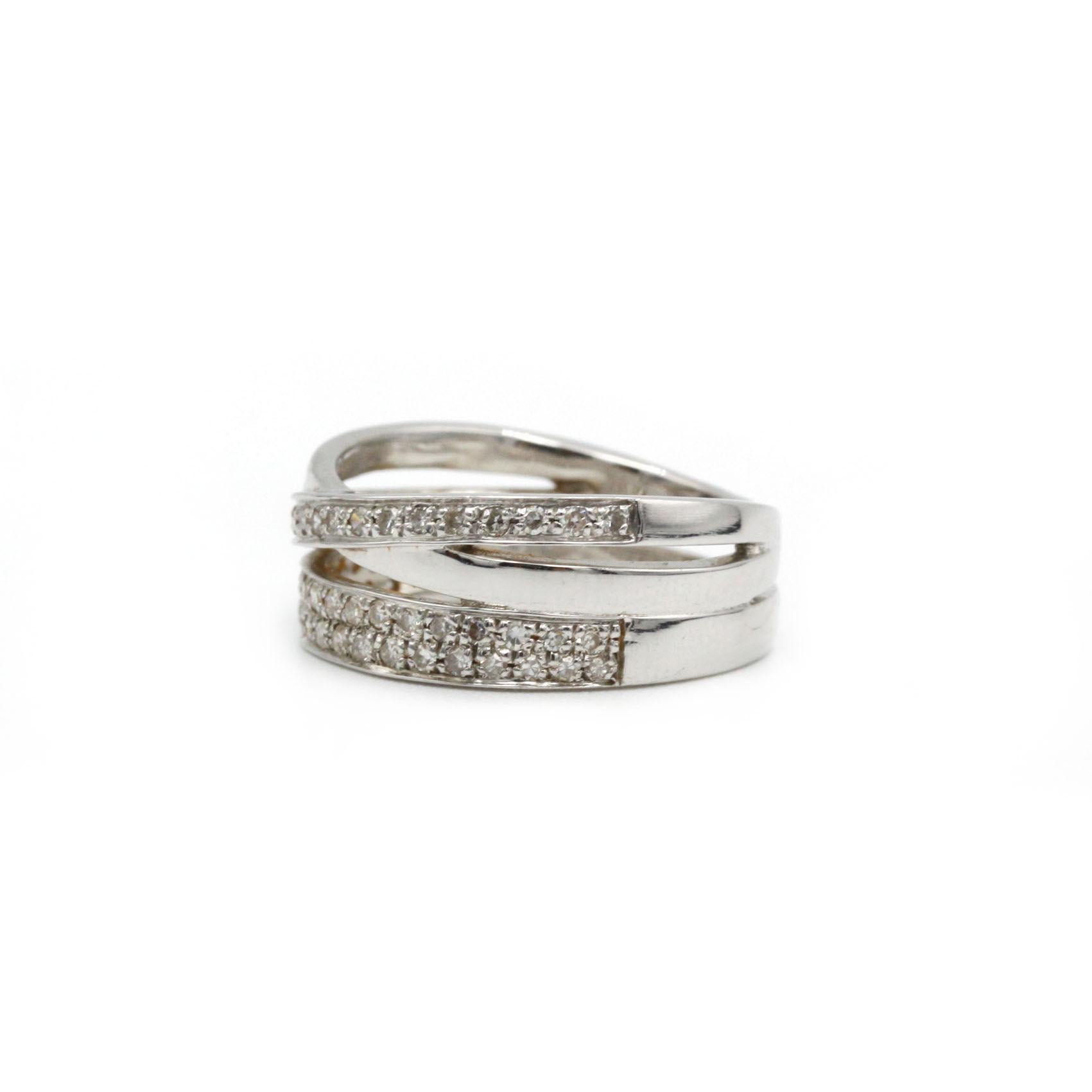 Dieser skulpturale Crossover-Ring ist aus 18 K Weißgold (750‰) gefertigt und mit 55 Diamanten im Brillantschliff mit einem Gesamtgewicht von ca. 0,50 ct aufwändig pavégefasst. Das Design besteht aus drei ineinander verschlungenen Bändern, von denen