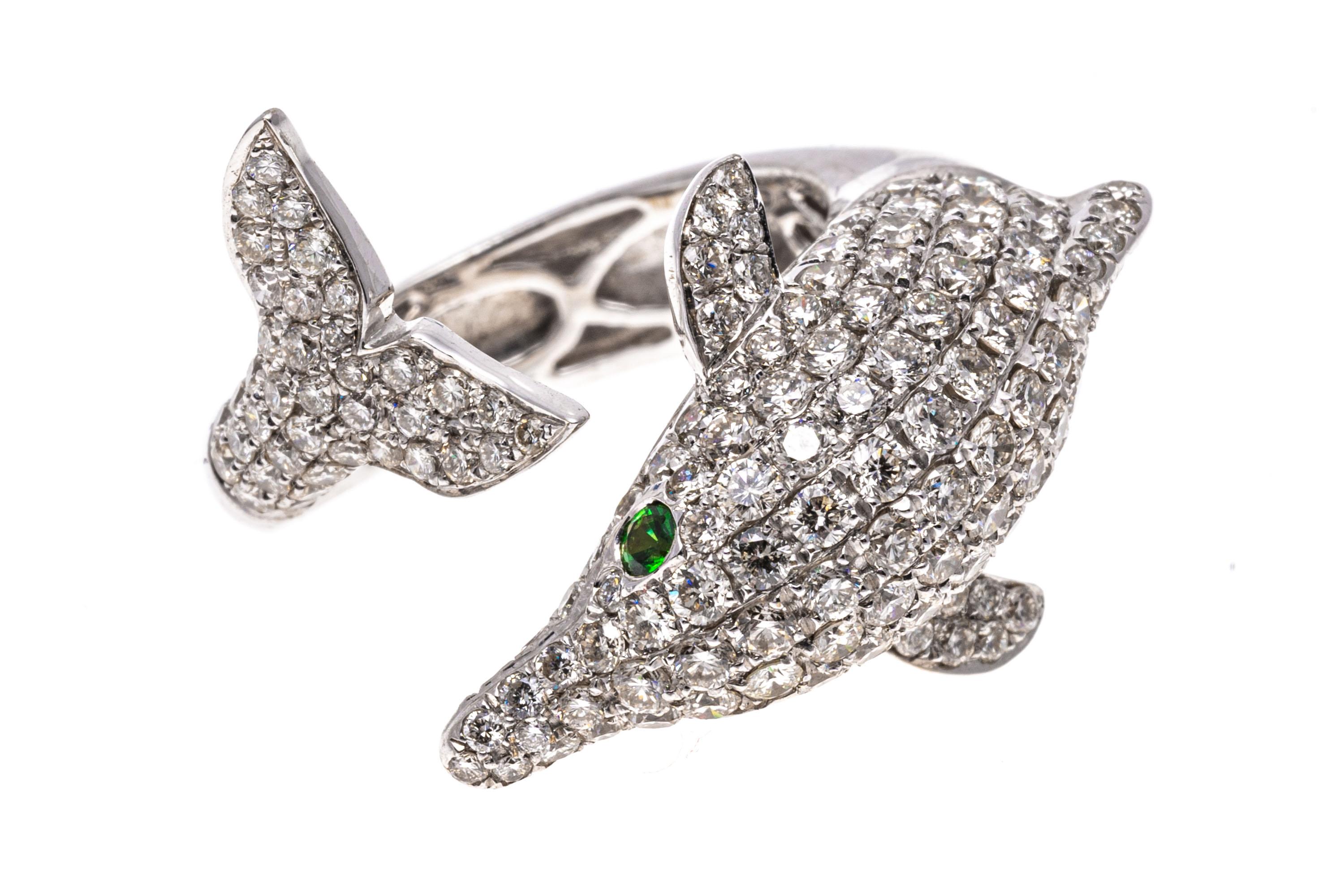 18k white gold ring. This gorgeous ring is a white gold, figural dolphin, with the head and tail as the bypass, pave set with round faceted diamonds, approximately 1.32 TCW. The ring is finished by round faceted, green tsavorite eyes, approximately