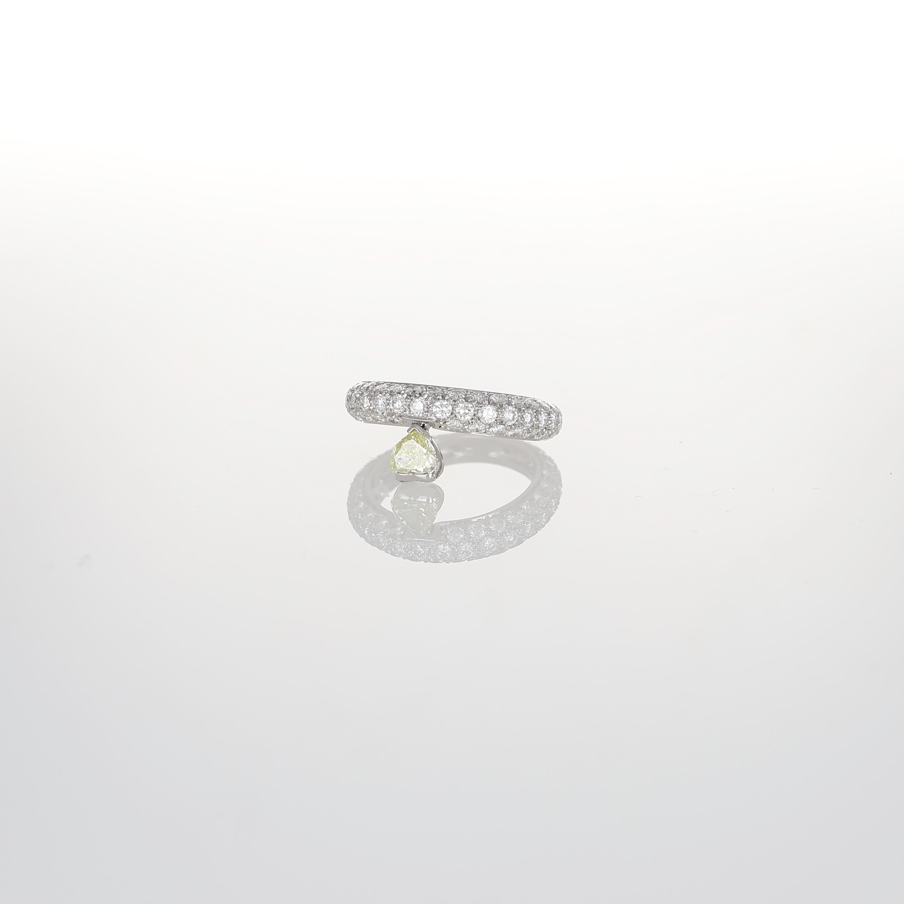 Interprétation raffinée et moderne de l'élégance classique, cette bague en or blanc 18 carats présente un pavage complet de diamants blancs taille brillant totalisant 1,87 carats. Le design épuré est rehaussé par un étonnant diamant jaune fantaisie