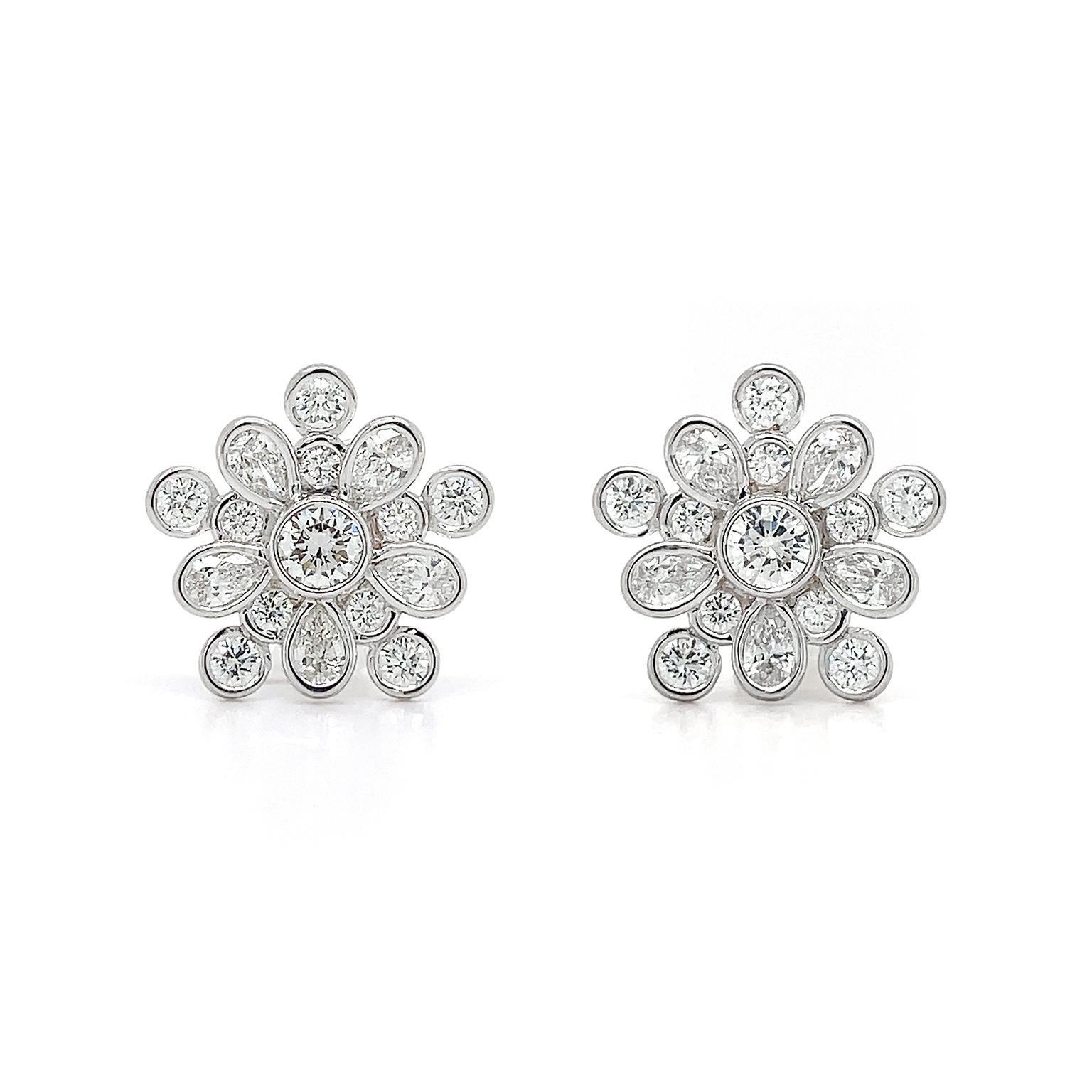 The coruscating radiance of diamonds is the essence of these earrings. A single round diamond is the heart of the pattern, while 5 pear-shaped diamonds radiate outward. In between each pear-shaped diamond is an individual round diamond, while a
