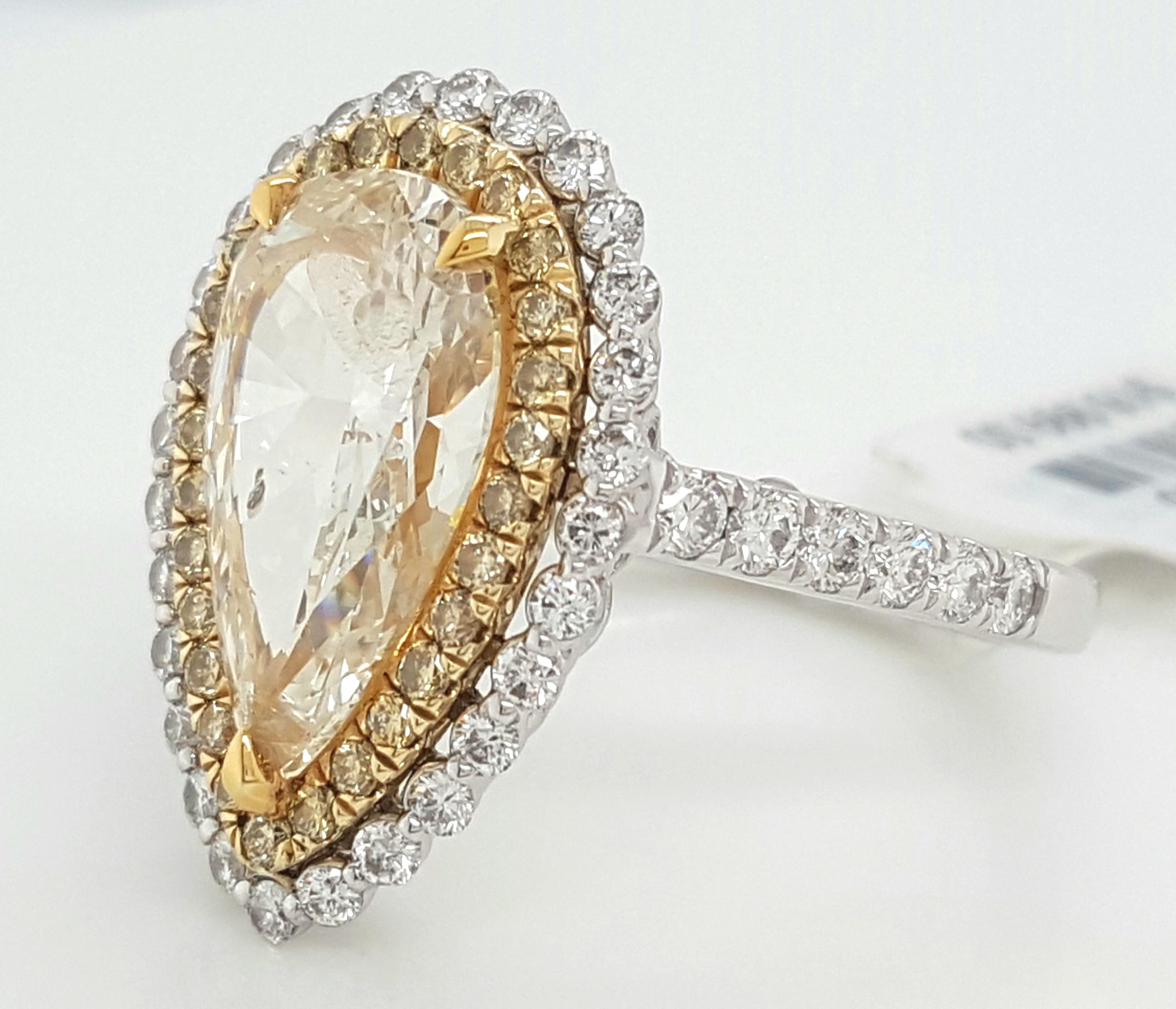 This excellent custom designed pear shape halo ring is absolutely incredible. The center is an elegant elongated pear shape diamond center with a light yellow color ranging from Q to R on the color grading scale and an I1 in clarity. The brilliance