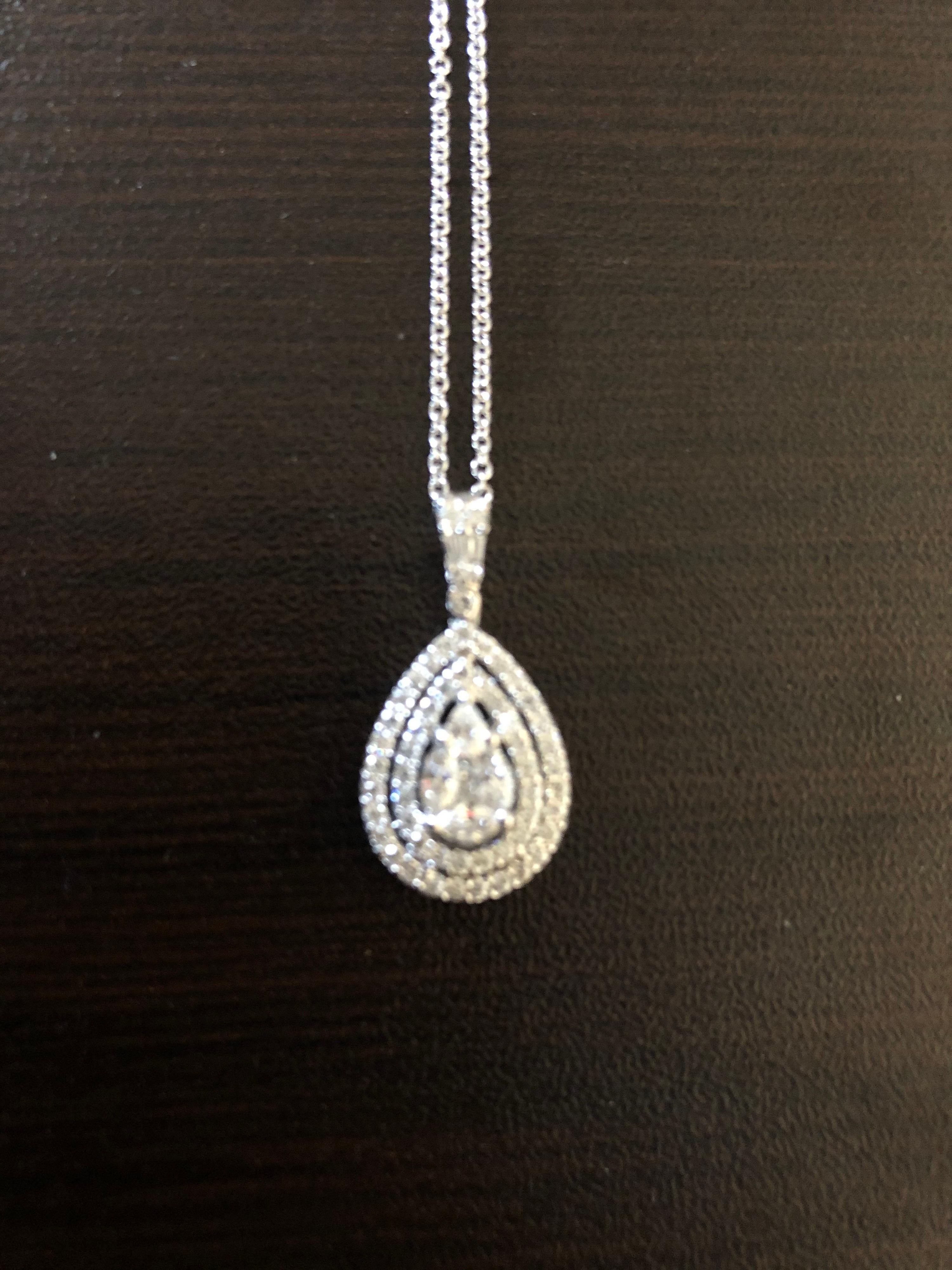 Pear shaped diamond pendant with double halo of round stones set in 18K white gold. The center is a princess in the middle with 4 marquise around it to create the illusion of a single pear diamond. The total carat weight of the pendant is 1.47. The