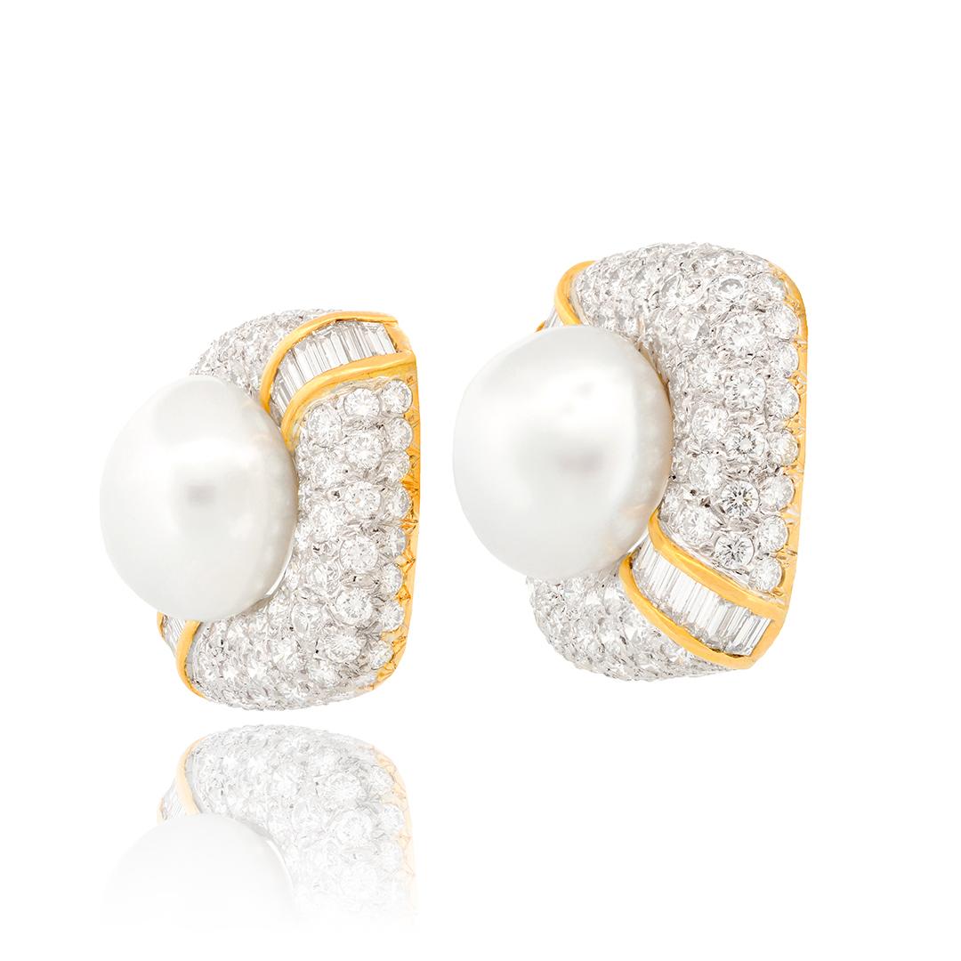 This pair of cultured pearl stud earrings are scattered with 20 bezel set diamonds weighing approximately 2.60 carats combined with GH coloring and VS clarity. The pearls measure 14.22mm and 14.70mm in diameter.
- 18k White Gold
- Cultured Pearls,