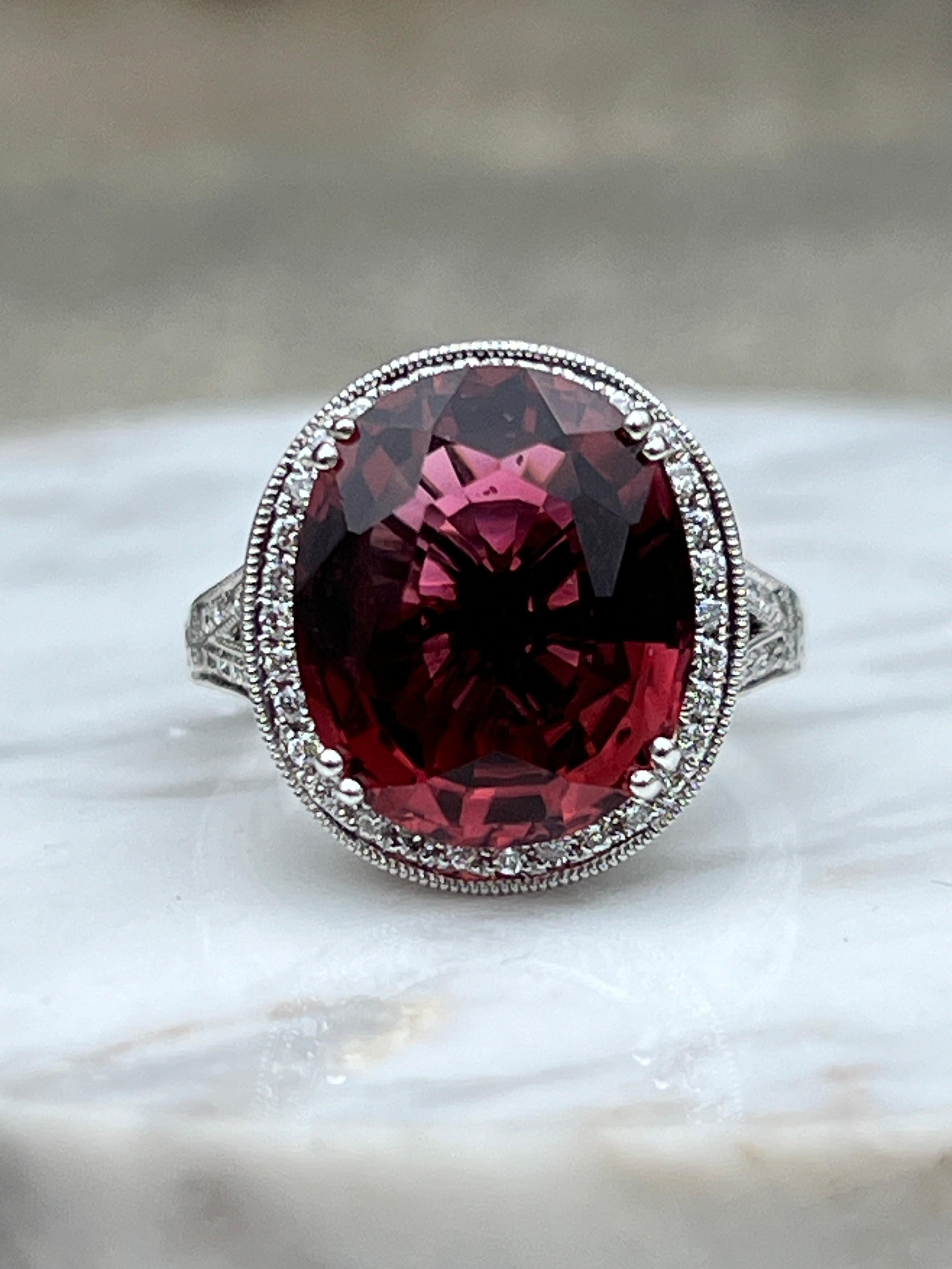 One vintage inspired 18 karat white gold filigree finish ring set with one oval 15mm, 8.39 carat pink tourmaline, and fifty-six round brilliant diamonds approximately 0.30 total carat weight with matching G/H color and VS clarity. This ring is a