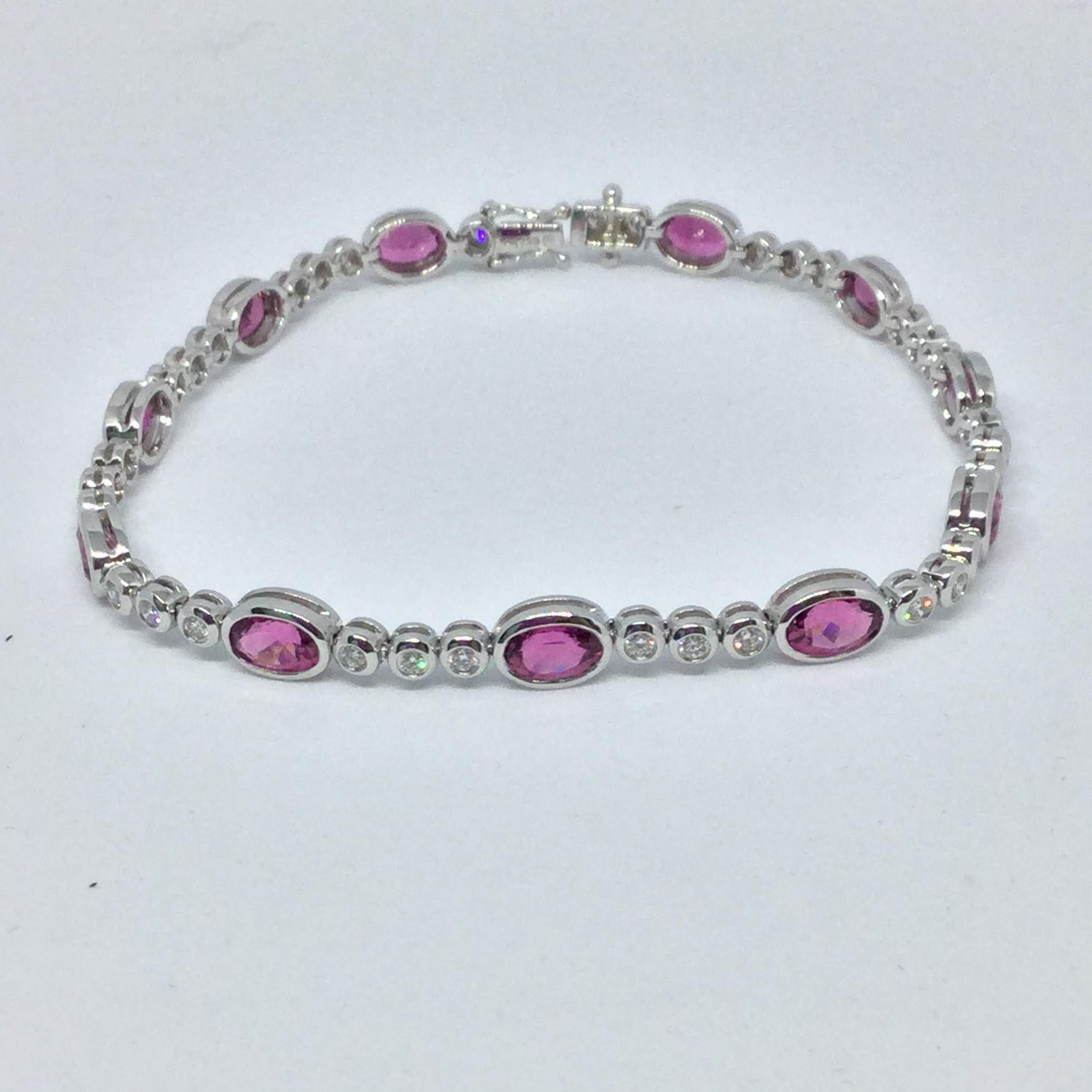 18K white gold pink tourmaline and diamond bracelet. Bracelet contains 11 oval cut pink tourmaline weighing 5.05 ctw and medium to dark pink in color. The bracelet contains 33 round brilliant cut diamonds weighing 0.72 ctw. The bracelet in 7 inches