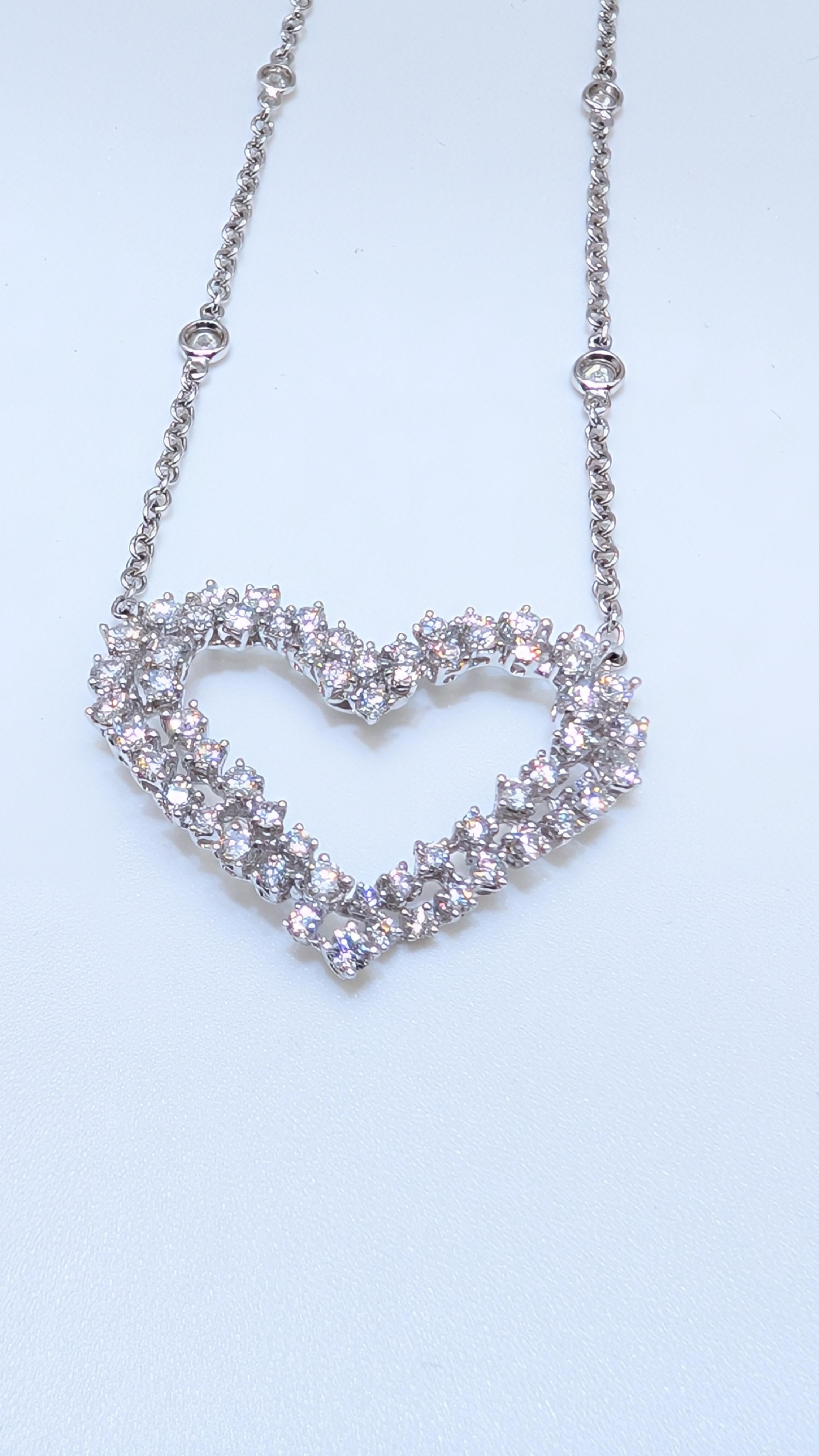 Questo elegante ciondolo presenta un design in oro bianco a 18 carati con un diamante a forma di cuore a due file al centro. I diamanti sono incastonati, in modo da mostrare il loro brillante splendore. Il pendente è sospeso da una collana con