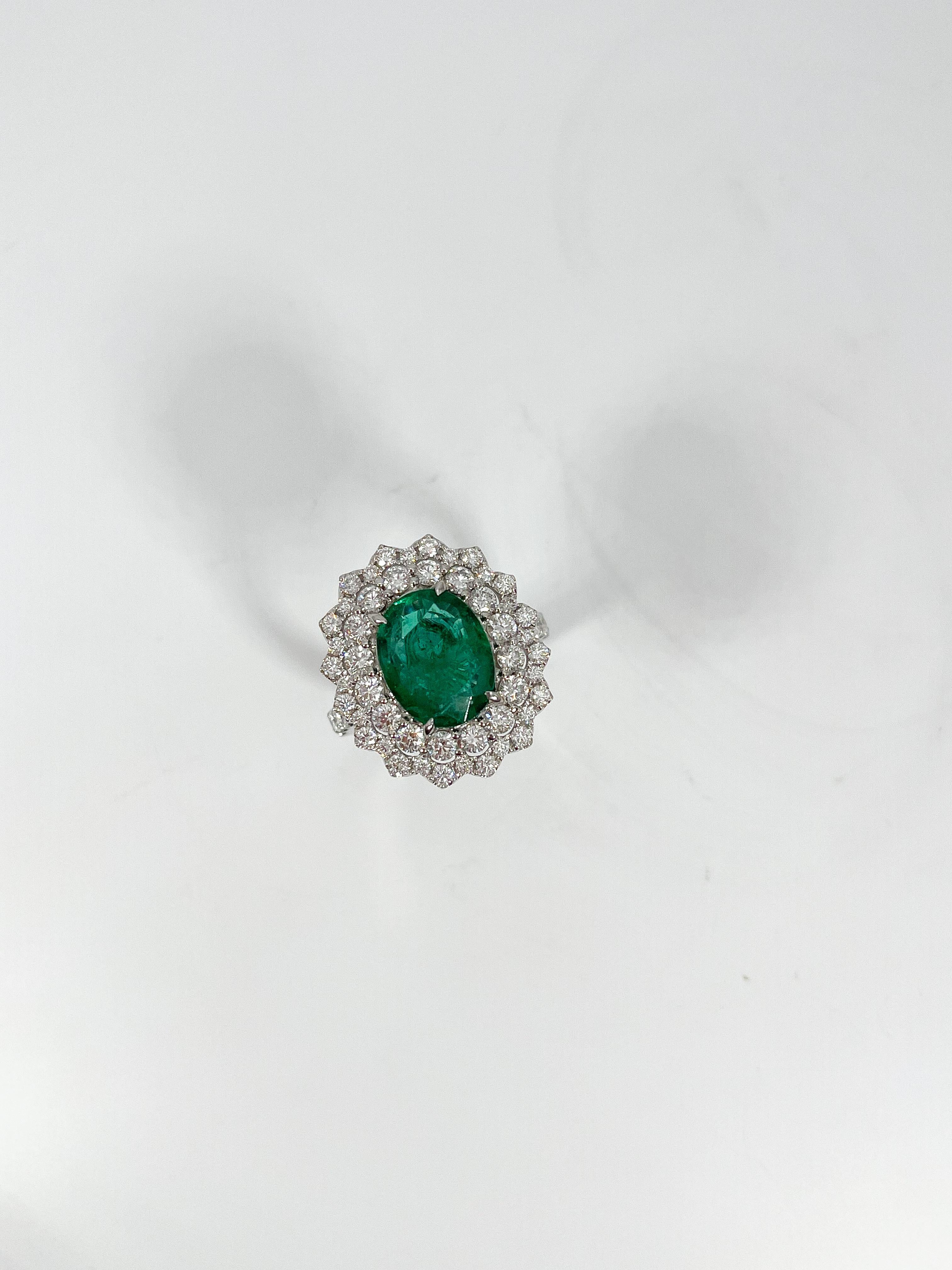 Ladies size 7 18k white gold ring prong and bead set with an oval brilliant cut emerald and round brilliant cut diamonds. Total item weight is 9.9 grams. Comes with AJI Certification. 
Emerald Attributes:
Shape and Cut- Oval brilliant