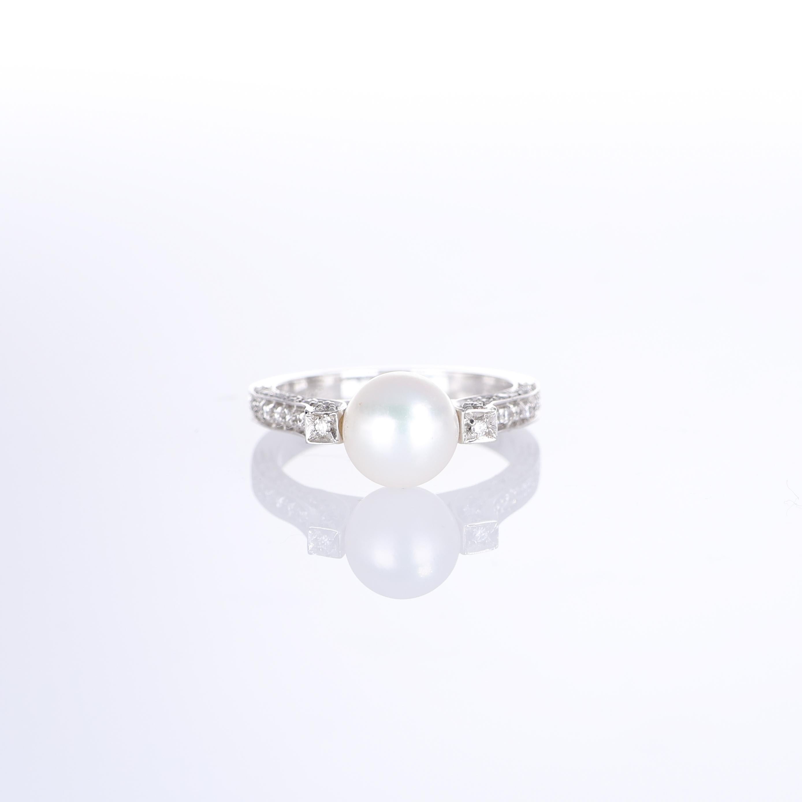 A refined 18k white gold ring featuring a luminous 8mm white pearl as its centerpiece. The band is adorned with a delicate pavé setting of natural white diamonds, totaling 0.32 carats, enhancing the ring’s elegance and brilliance. The timeless