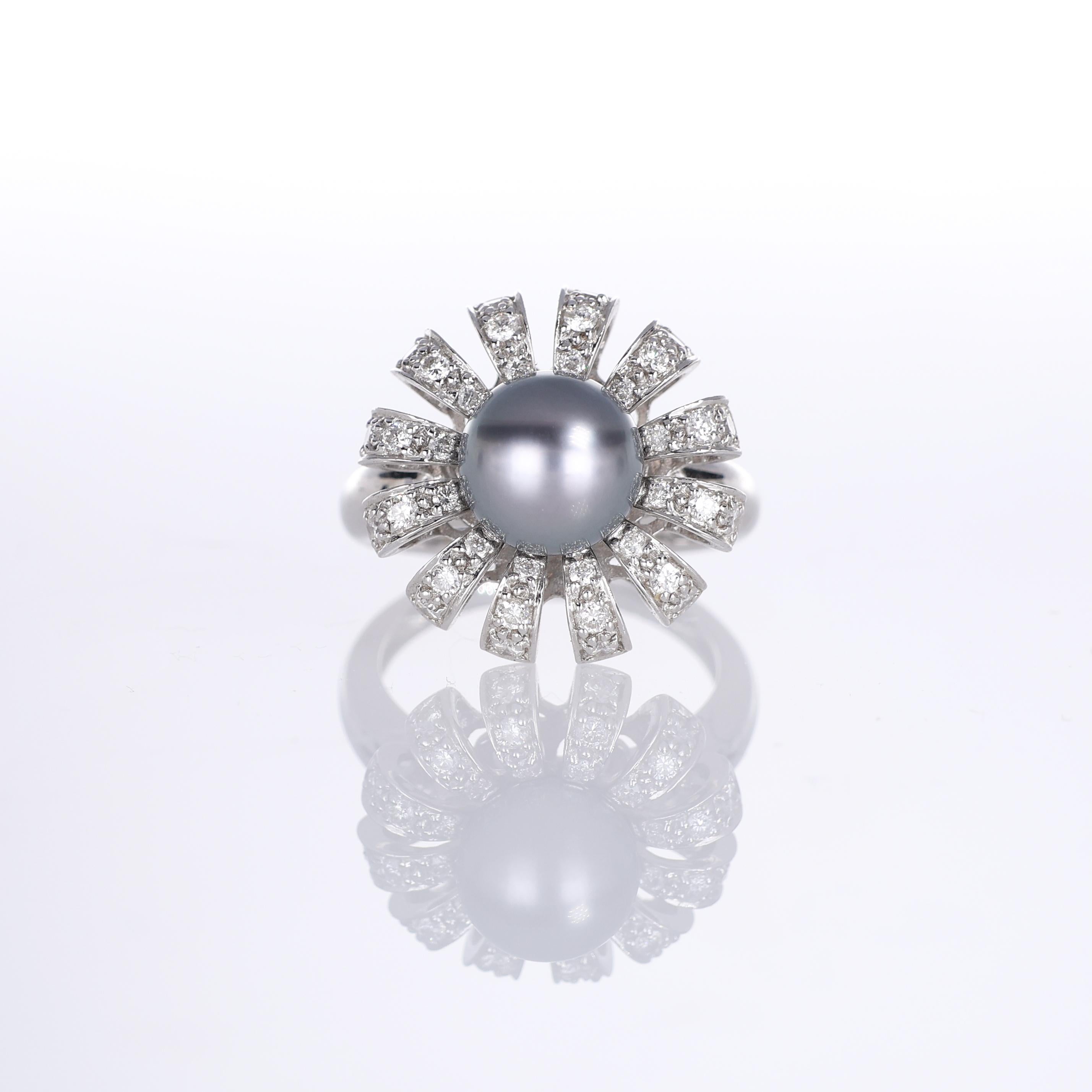 A striking 18K white gold ring featuring a luminous black pearl at its center, surrounded by a floral-inspired arrangement of pavé-set brilliant-cut diamonds. The radiating petal-like structure enhances the pearl’s natural elegance, creating a