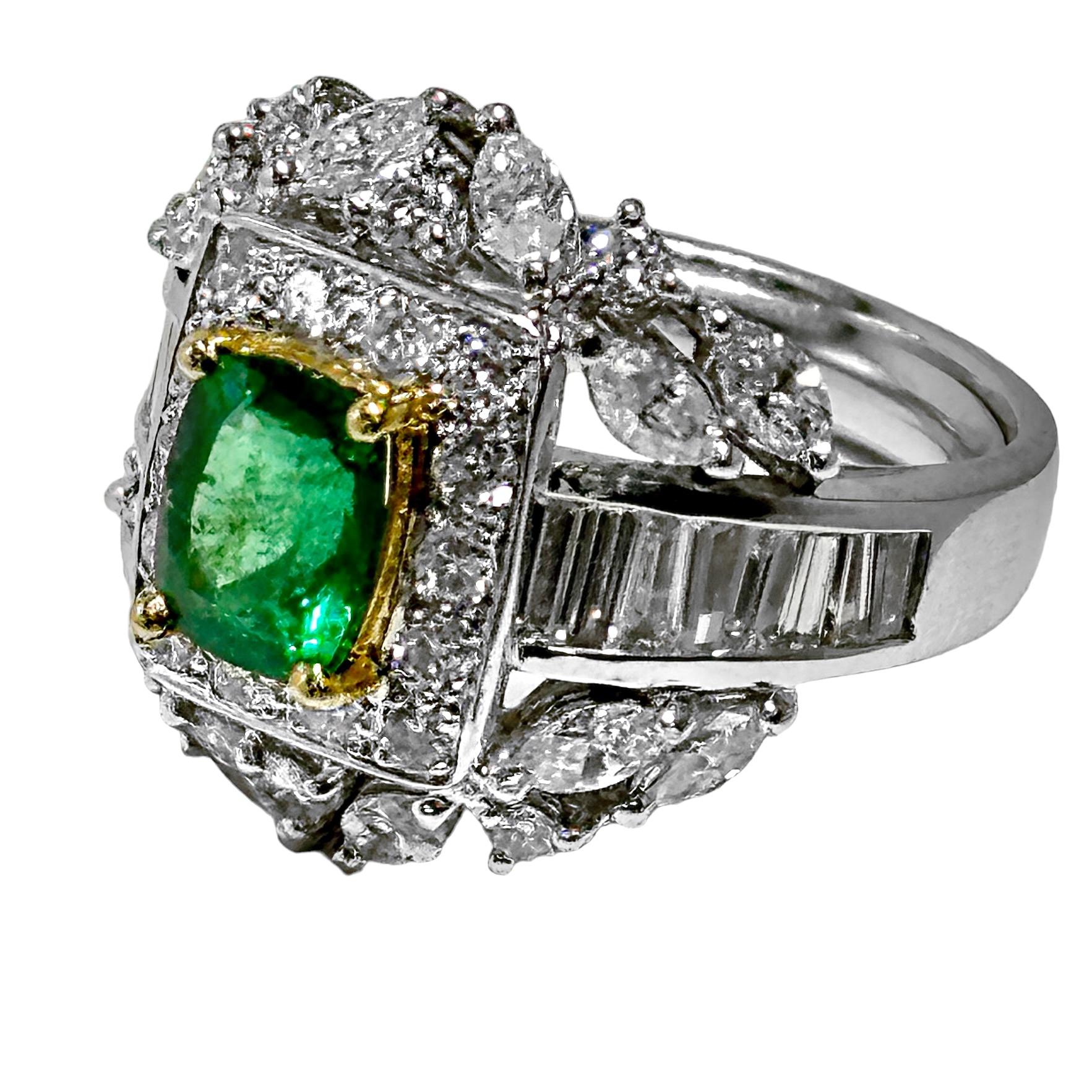Ein Cocktailring aus 18 Karat Weißgold und Diamanten, in dessen Mitte ein Smaragd im Kissenschliff liegt. Der 1,27-karätige Smaragd ist in Gelbgold eingefasst und von vierzehn runden Diamanten im Brillantschliff von insgesamt G Farbe und VS2/SI1