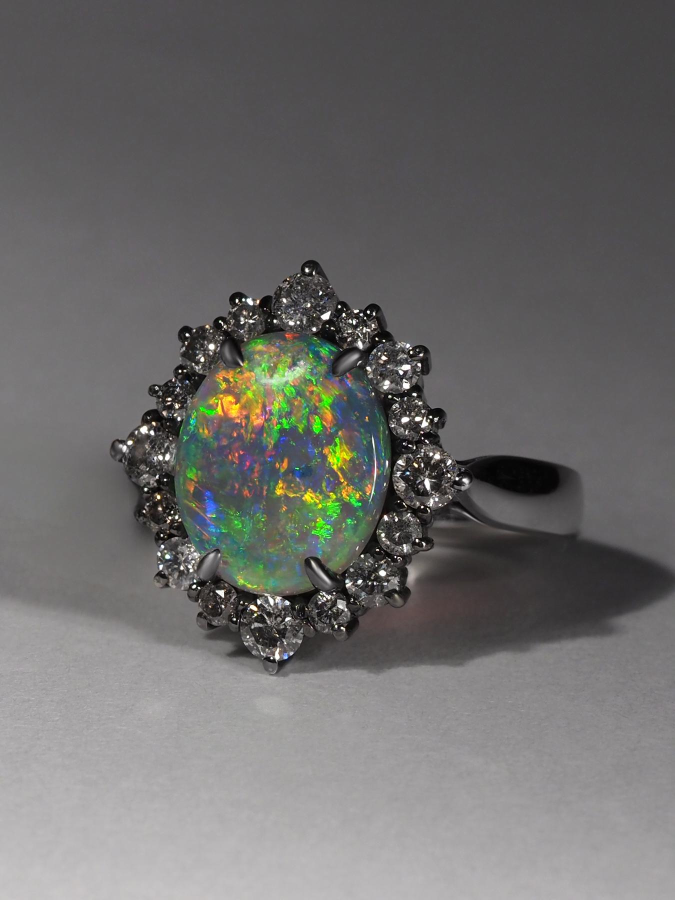 Un anello con un opale scuro naturale incastonato in oro bianco 18 carati e argento 925.

Circondato da 16 diamanti sul cerchio interno e 16 diamanti sul cerchio esterno.
Origine dell'opale: Australia
Origine del diamante: India
Peso dell'opale: