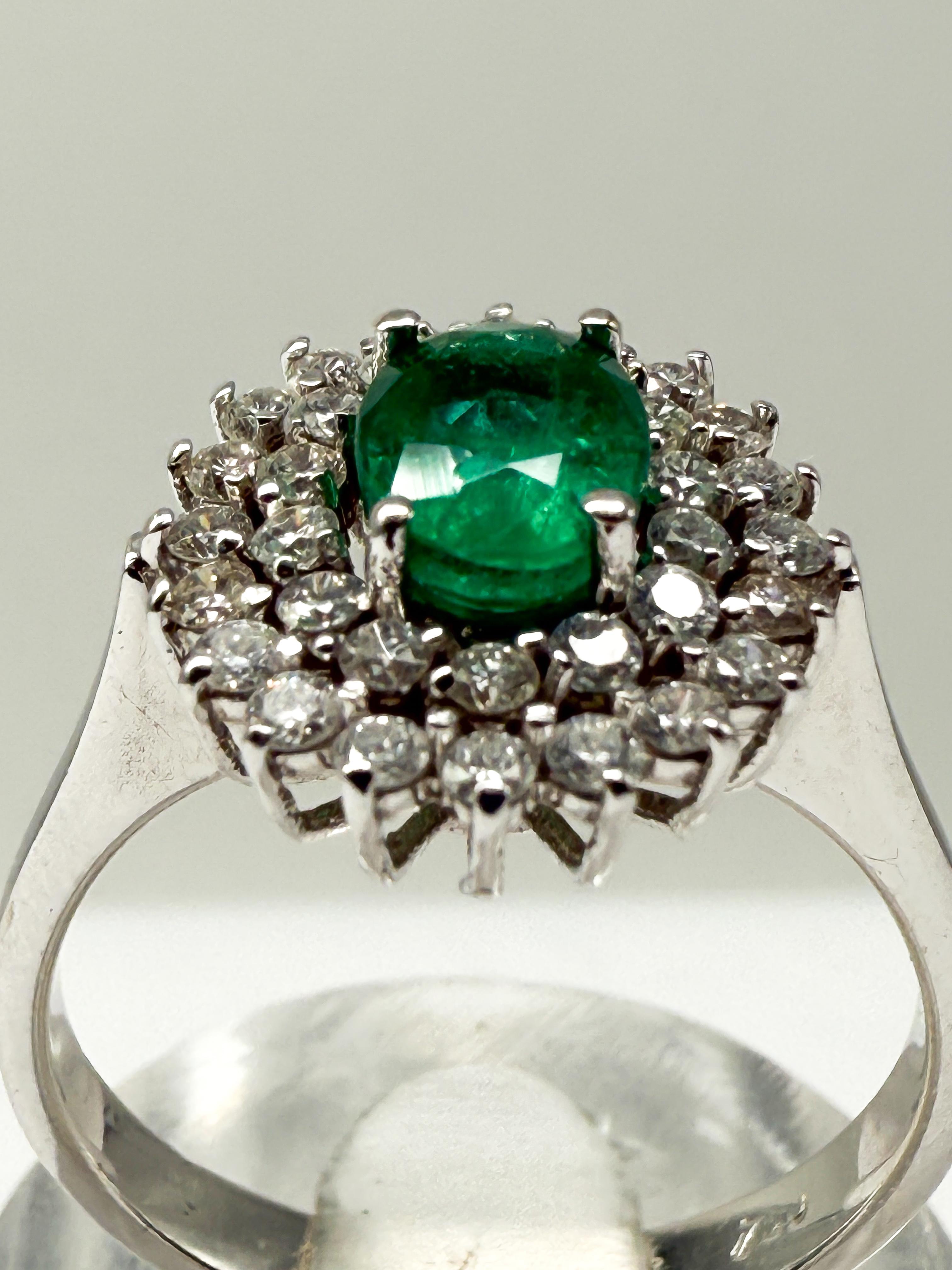This elegant ring, crafted from fine 18-karat white gold, is a captivating piece of jewelry that stands out for its superior craftsmanship and stunning design. At its heart lies a natural, oval-cut emerald in a vivid green hue, measuring 7.2 x 5.3