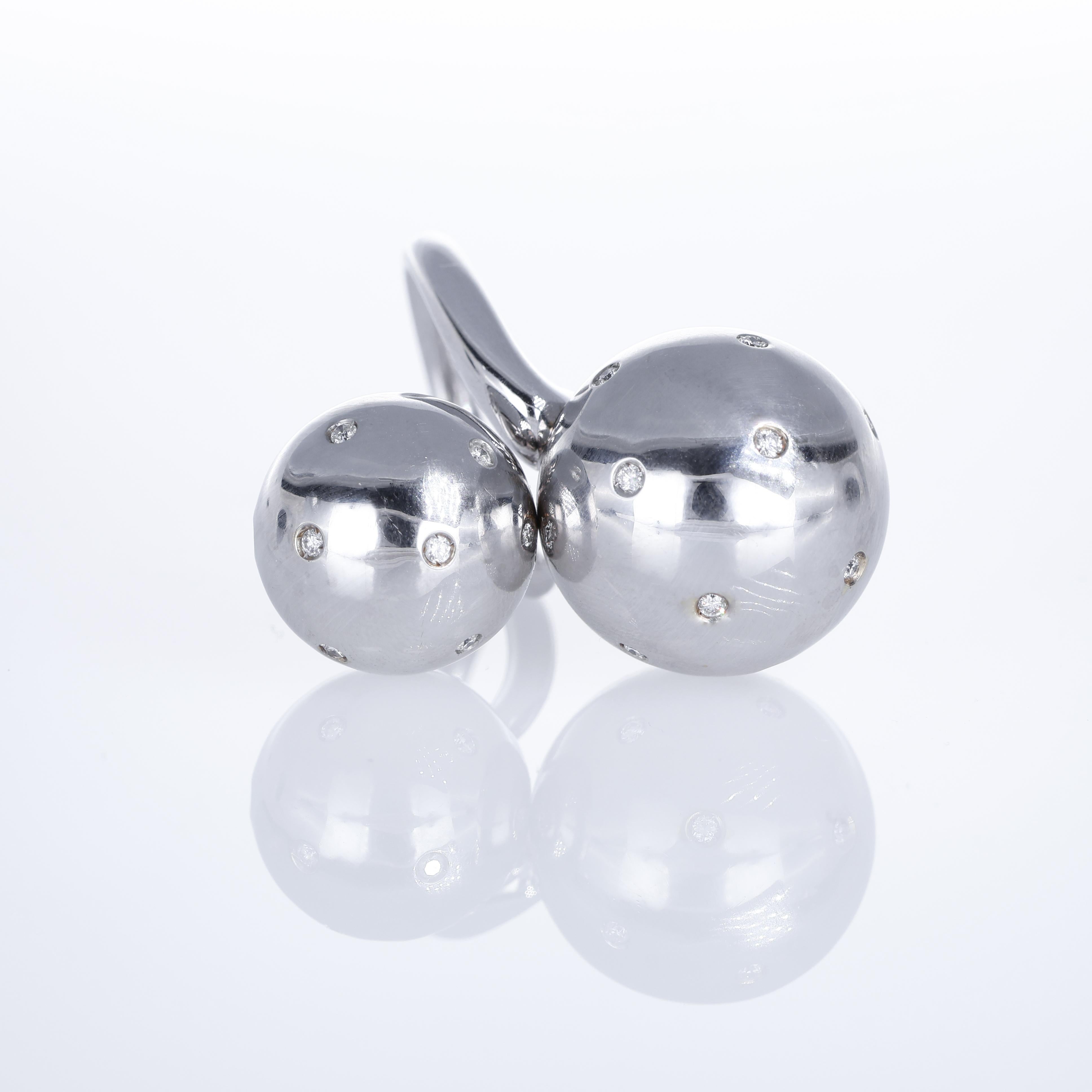 A contemporary 18K white gold ring featuring two removable spheres, each adorned with scattered brilliant-cut diamonds. The innovative design allows the spheres to be unscrewed, offering versatility and a bold aesthetic. A striking piece that blends