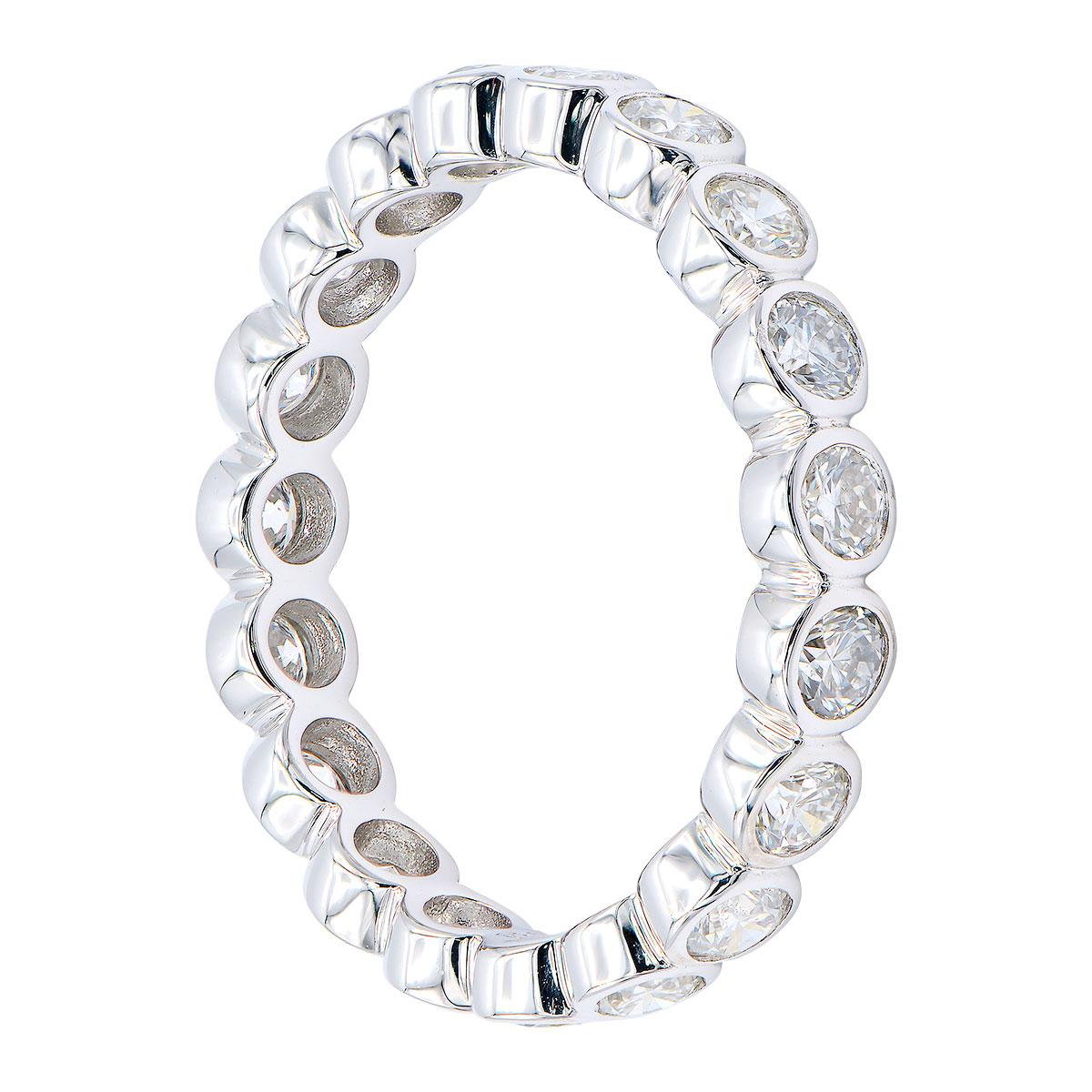 This beautiful eternity band has diamonds going all the way around which are bezel set in 2.6 grams of 18 karat white gold. There are 17 round VS2, G color diamonds totaling 1.12 carats. The round shape made by the setting around each diamond makes