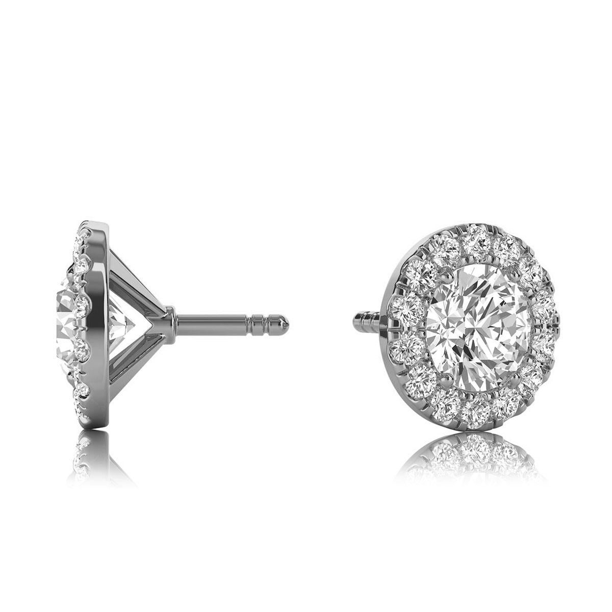 These delicate earrings feature two round shaped diamonds that are approximately 0.70-carat total weight (4.5mm) encircled by a halo of perfectly matched 28 round brilliant diamonds in about 0.28-carat total weight. The earrings are measuring at