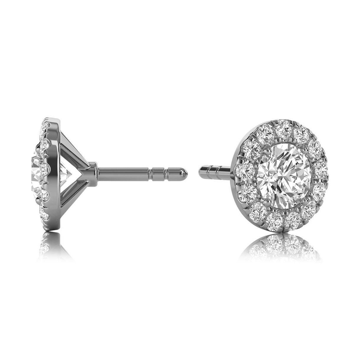 These delicate earrings feature two round shaped diamonds that are approximately 0.50-carat total weight (4mm) encircled by a halo of perfectly matched 26 round brilliant diamonds in about 0.25-carat total weight. The earrings are measuring at 7mm