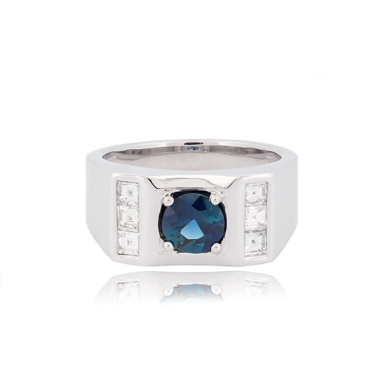 This 18 karat white gold gentleman’s ring is set with a center round faceted fine royal blue sapphire that weighs approximately 1.49 carats. The center stone is paired with six square baguette diamonds that weigh approximately 0.84 carats combined