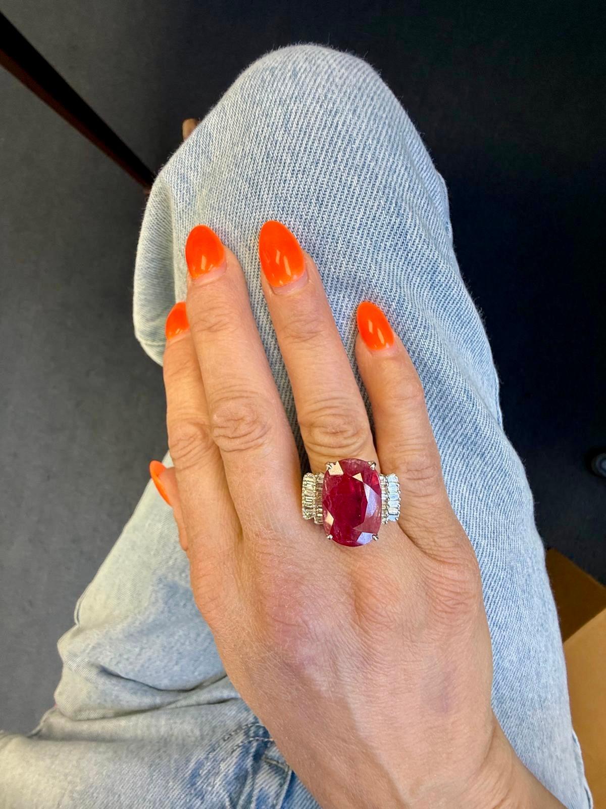Dieser kühne und glamouröse Cocktailring zeigt in der Mitte einen lebhaften, übergroßen Rubin, der von zwei strahlenden Flanken aus spitz zulaufenden Diamanten im Baguetteschliff akzentuiert wird, die in 18 Karat Weißgold gefasst sind. Die markante