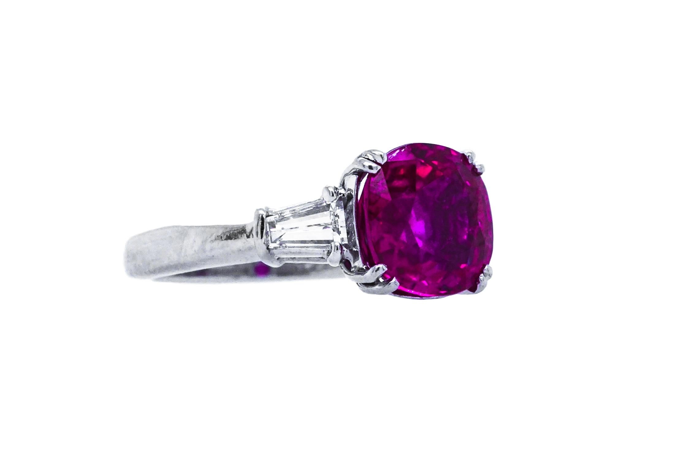 This Cartier White Gold, Ruby and Diamond ring centers one oval ruby approximately 3.34cts., and is flanked by 2 fancy-shaped diamonds approximately .40ct. and is a size 6 . This ring is is also not heated.  