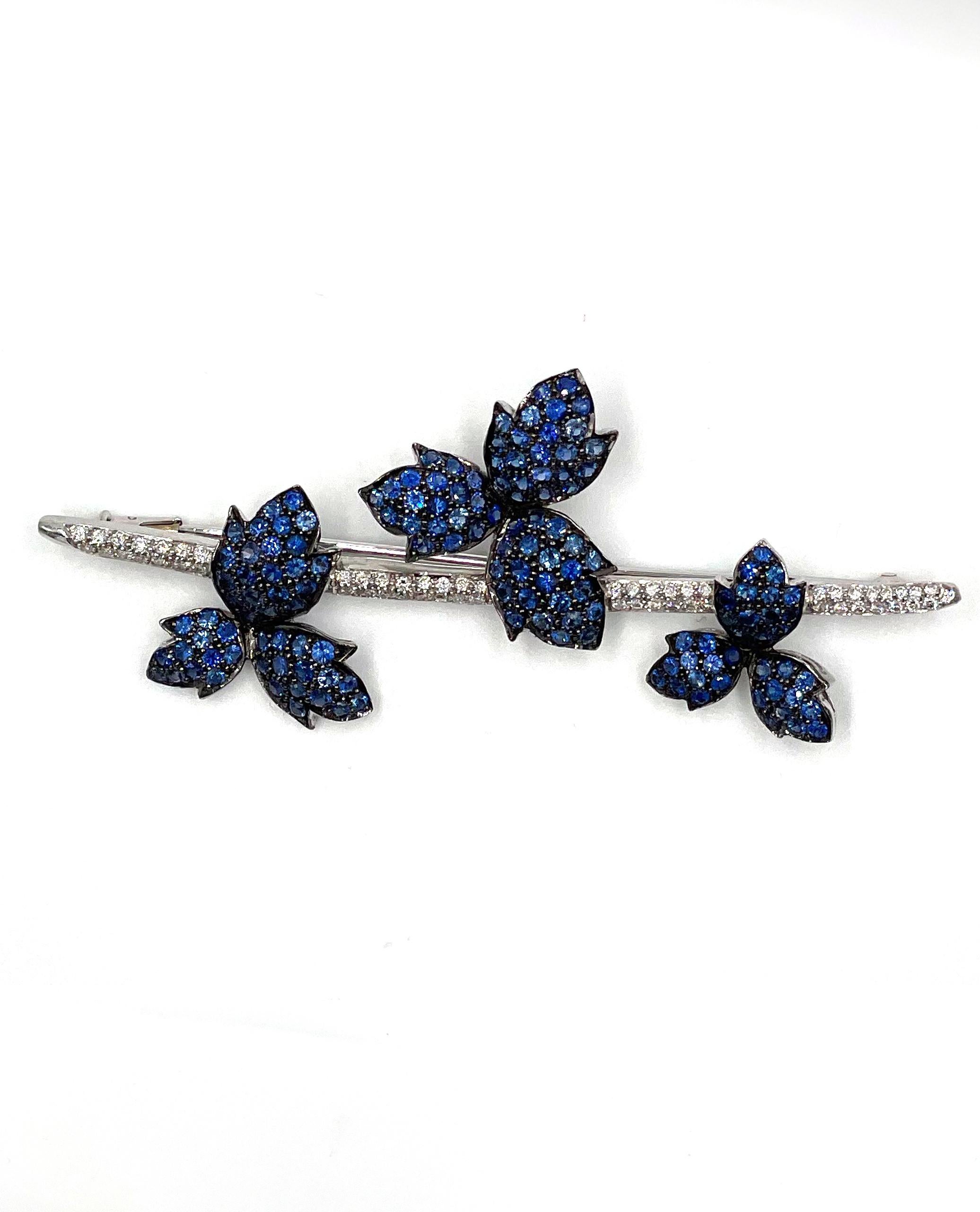 Pre owned vintage estate 18K white gold sapphire and diamond bar brooch with 58 pave set round brilliant cut diamonds approximately 0.38 carat total weight.  The brooch has a three leaf/floral clusters.  They are blackened white gold and bead set