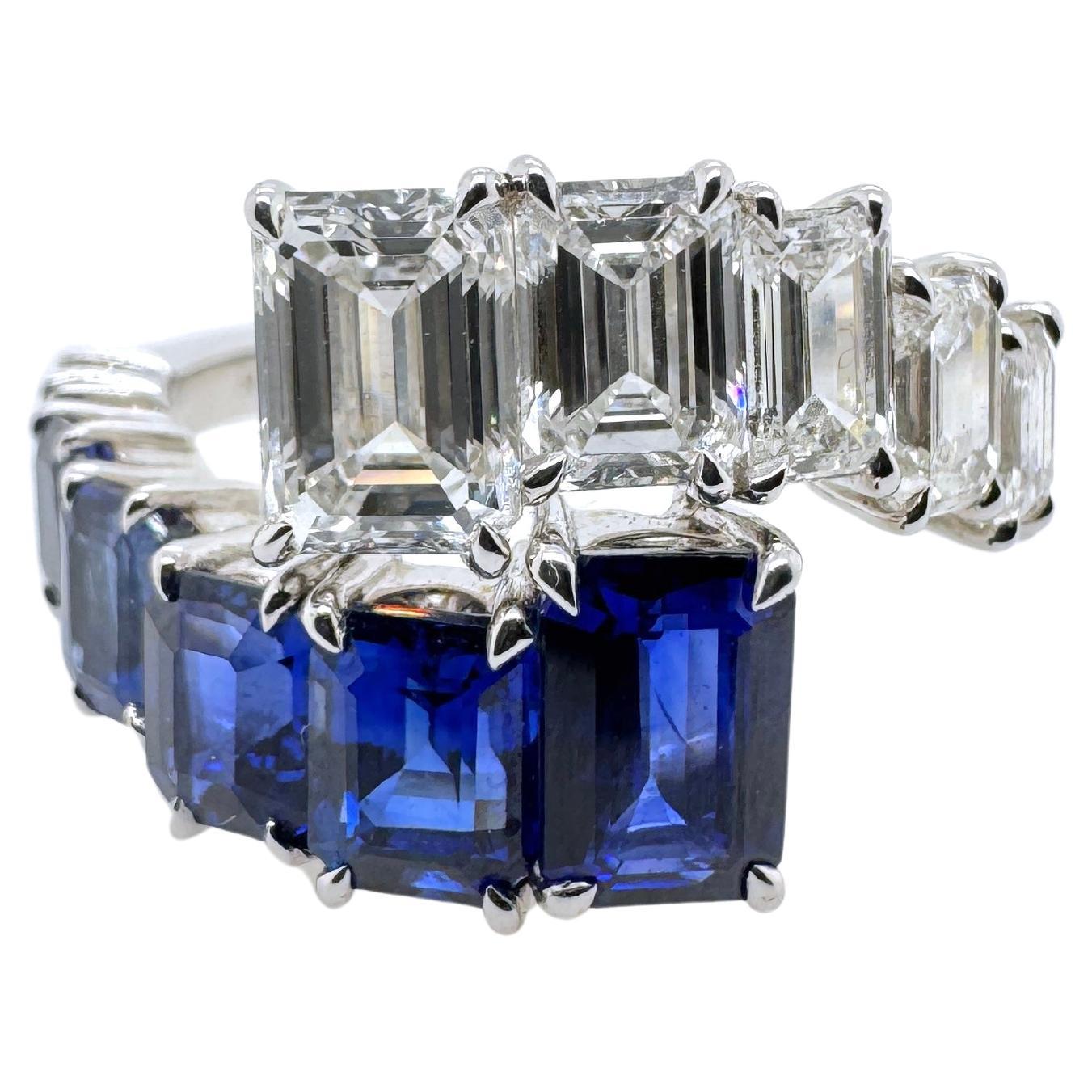 Elevate your collection with this striking contemporary bypass ring, crafted in luxurious 18 karat white gold. Bold yet elegant, it features a captivating contrast of royal blue emerald cut sapphires and high clarity emerald cut diamonds. The bypass