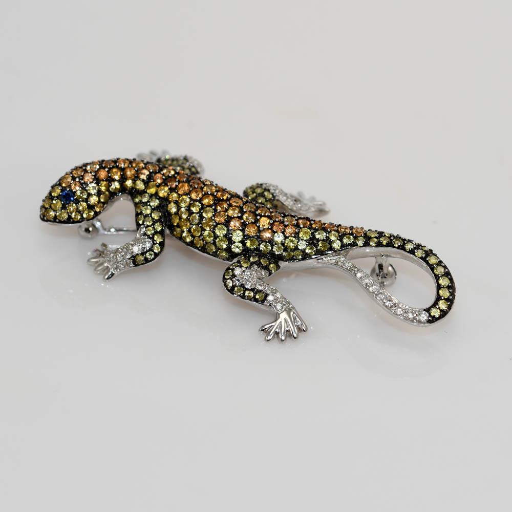 Custom made 18k white gold chameleon brooch with sapphires and diamonds.
Test 18k and weighs 10.8 grams.
The sapphires are yellow and brownish-orange colored, round brilliant cuts, 2.00 total carats.
There are two blue sapphires eyes.
The diamonds