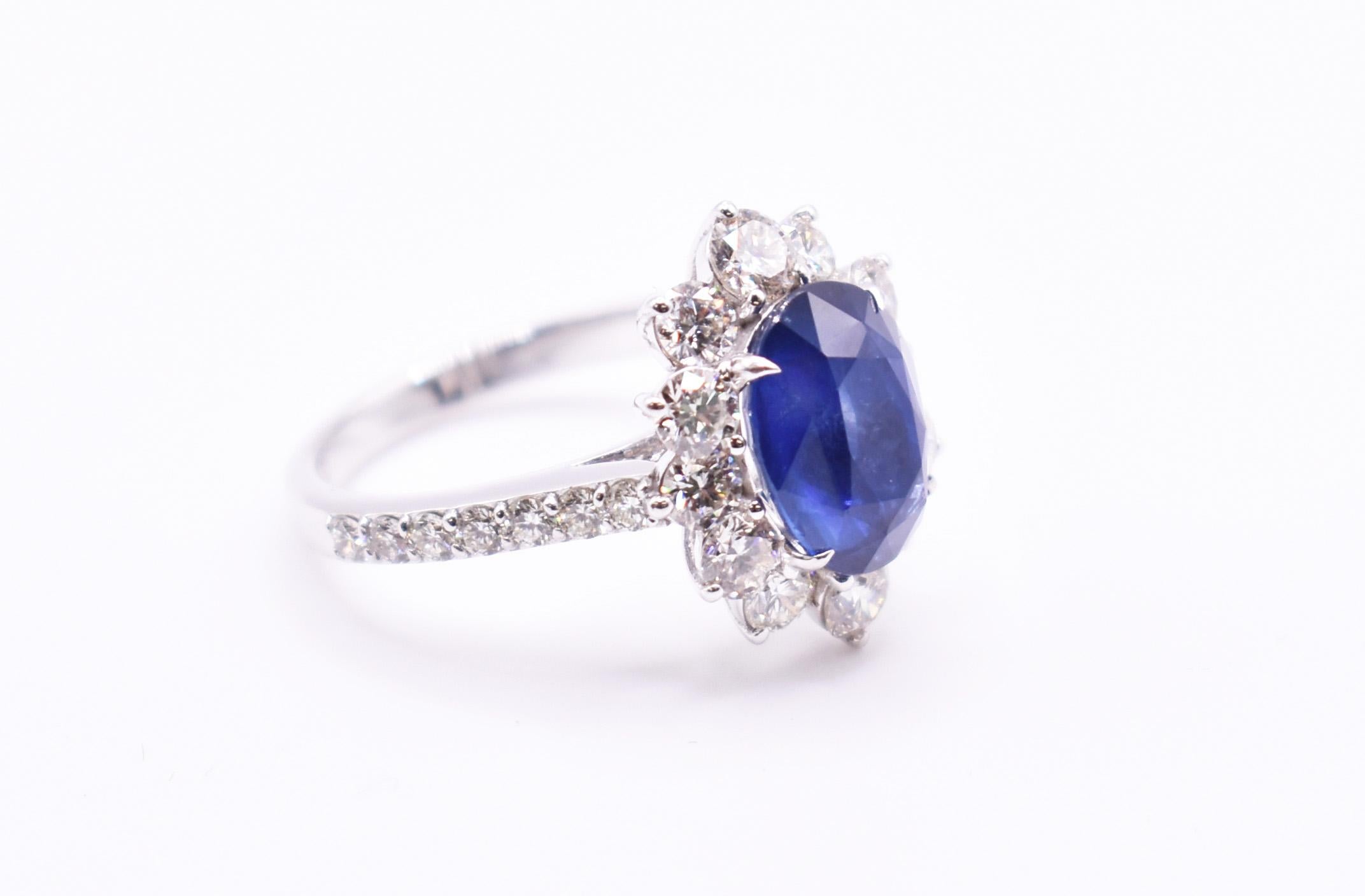 A stunning 18k white gold sapphire & diamond ring, featuring an oval cut sapphire in a prong setting, surrounded by 12 round cut diamonds, with a diamond studded band. Sapphire = 4.19ct Diamonds: 1.84ct. 

UK: O US: 7