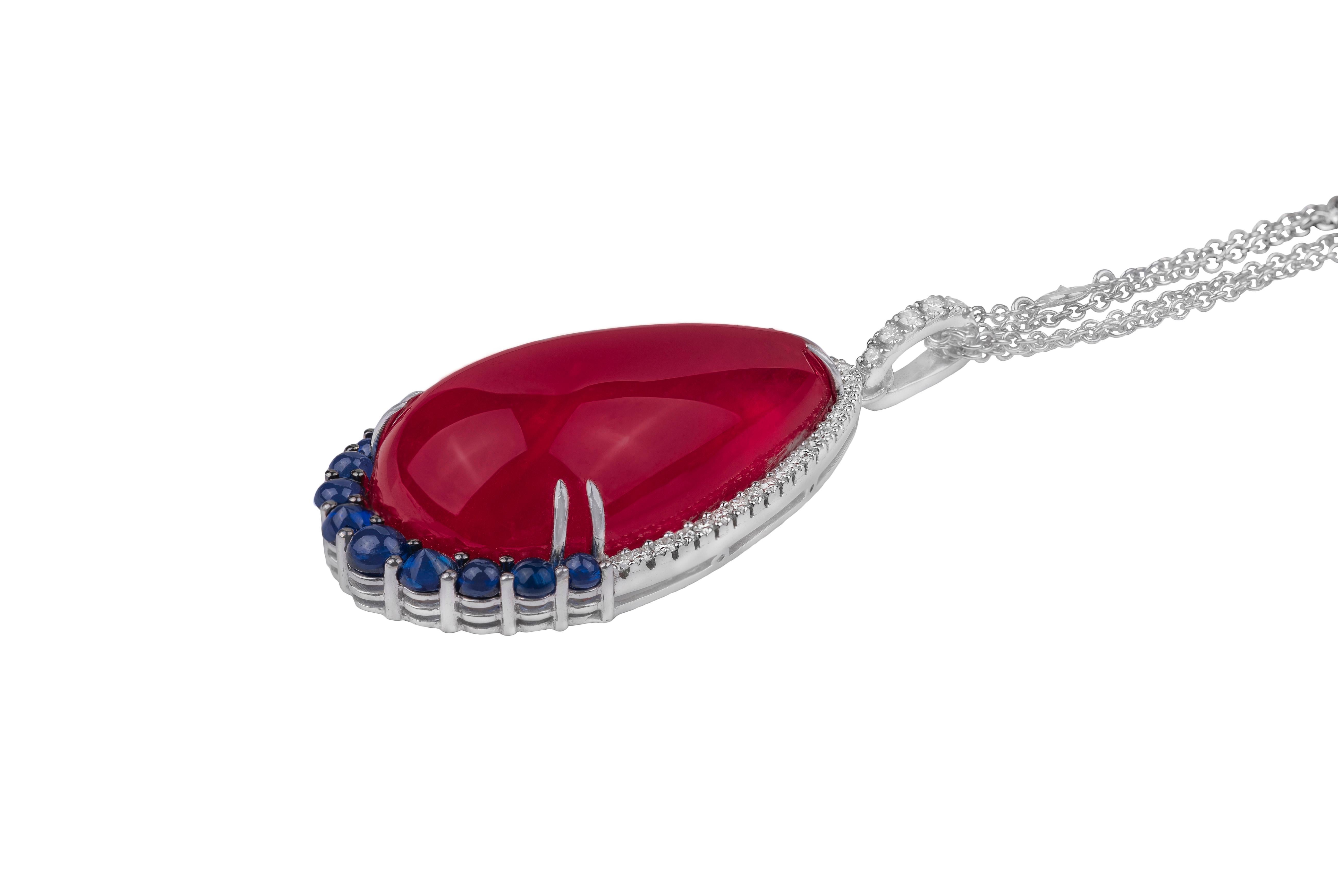 This elegant 18k white gold necklace is made in Italy by Fanuele Gioielli.    
The drop shaped pendant is composed by cabochon cut drop shaped ruby, nine cabochon cut round shaped sapphires and a row of brilliant cut white diamonds. Brilliant cut