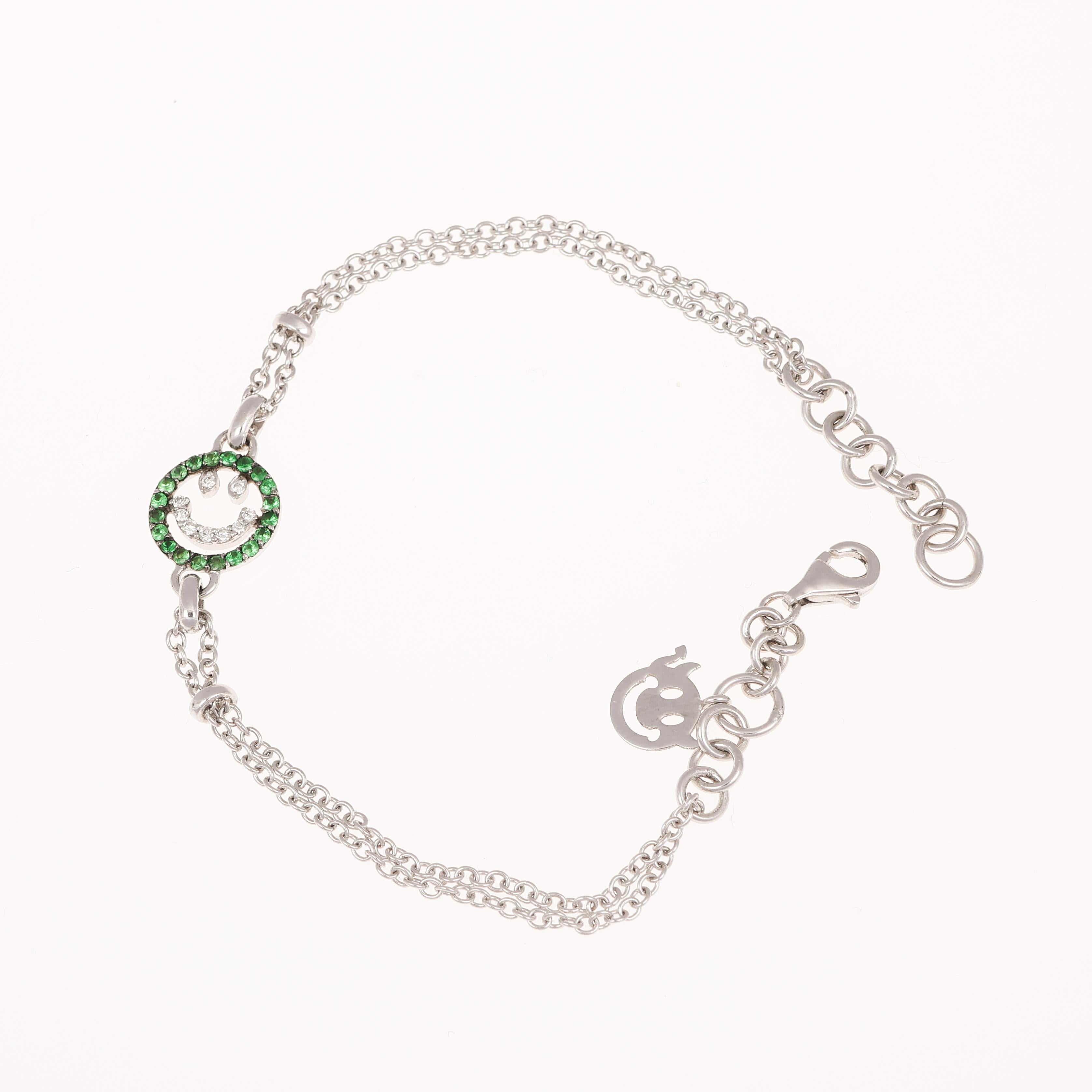 Un bracciale giocoso e raffinato realizzato in oro bianco 18 carati, con un motivo a faccina sorridente ornato da 0,09 carati di diamanti bianchi a taglio brillante e incorniciato da 0,23 carati di vibranti tsavoriti verdi. Il delicato design a